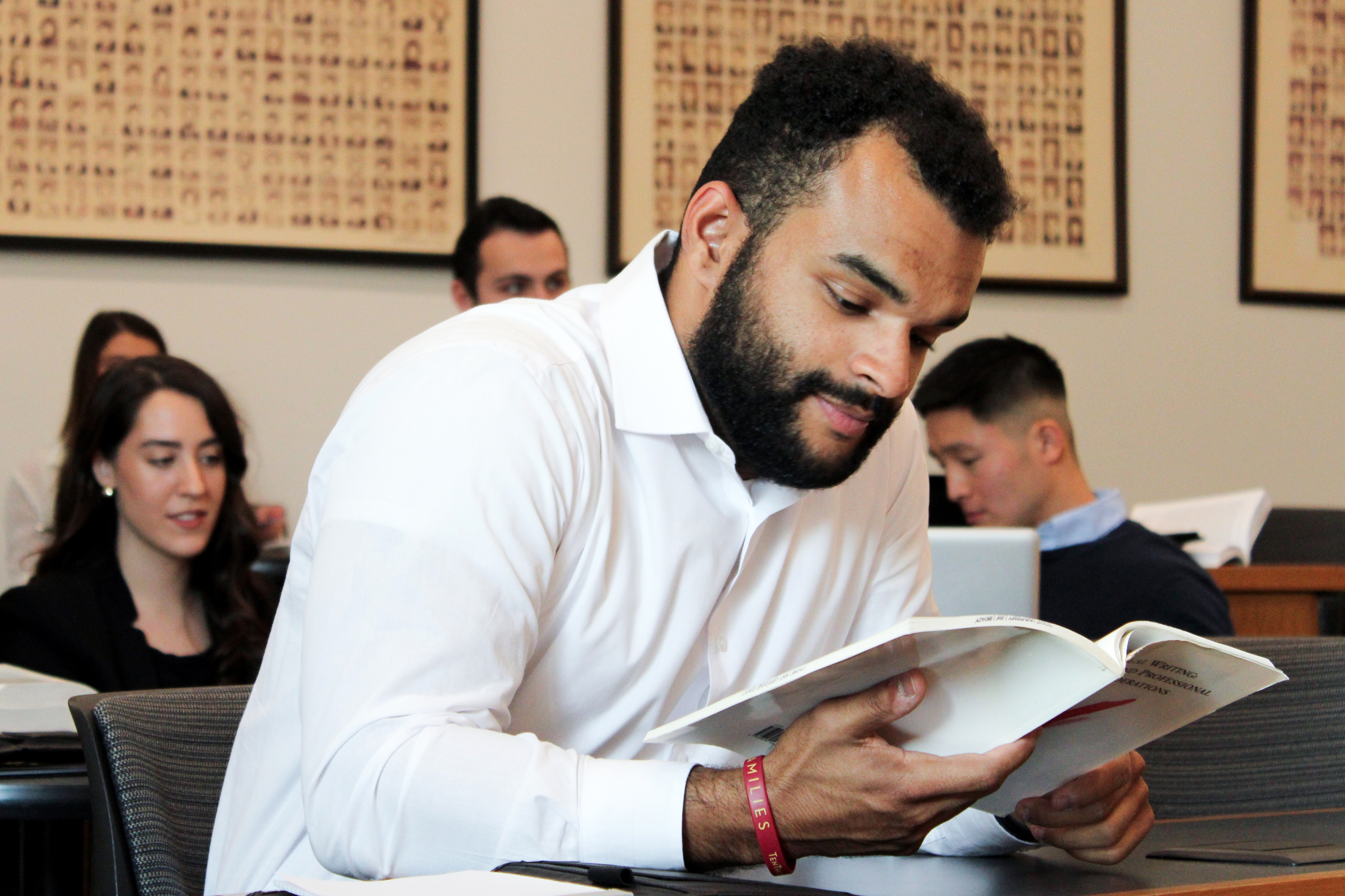 A student from Drake's Law, Politics, and Society program leans over a desk to read a brochure ahead of a J-Term trip