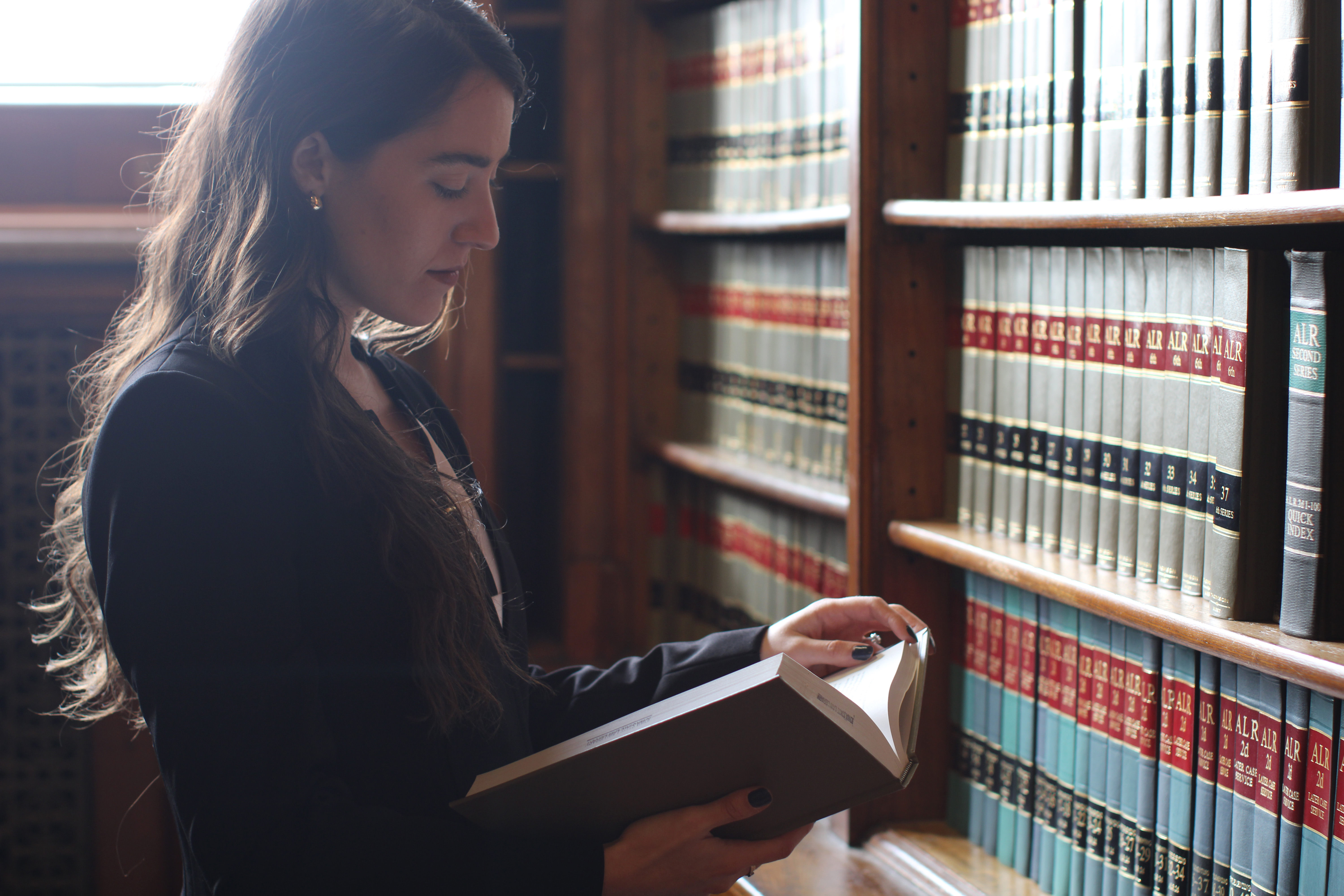 For a research project, a student from Drake's Law, Politics, and Society program reviews a reference book in the campus law library