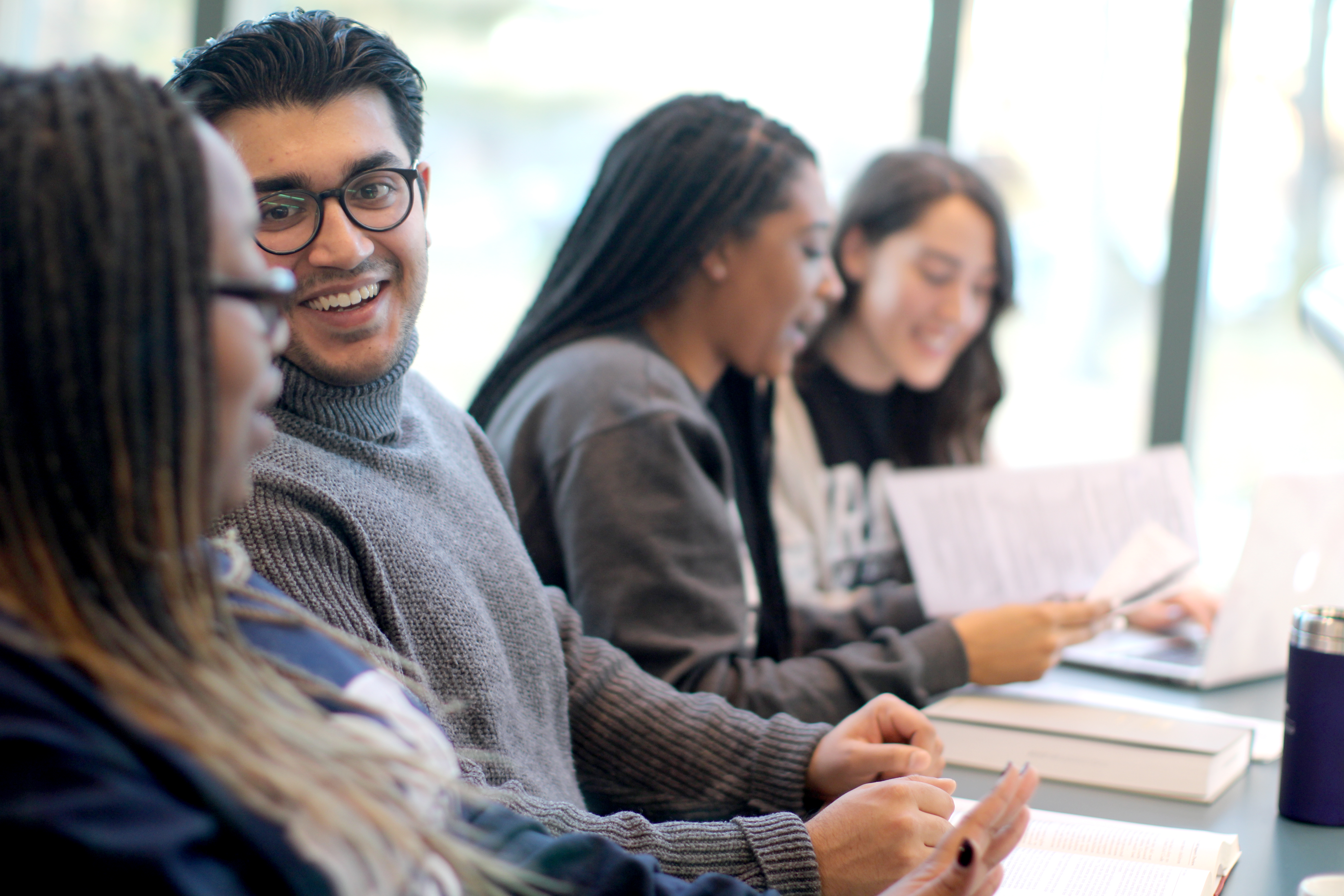 Students from Drake's Law, Politics, and Society program review books and packets in a classroom setting