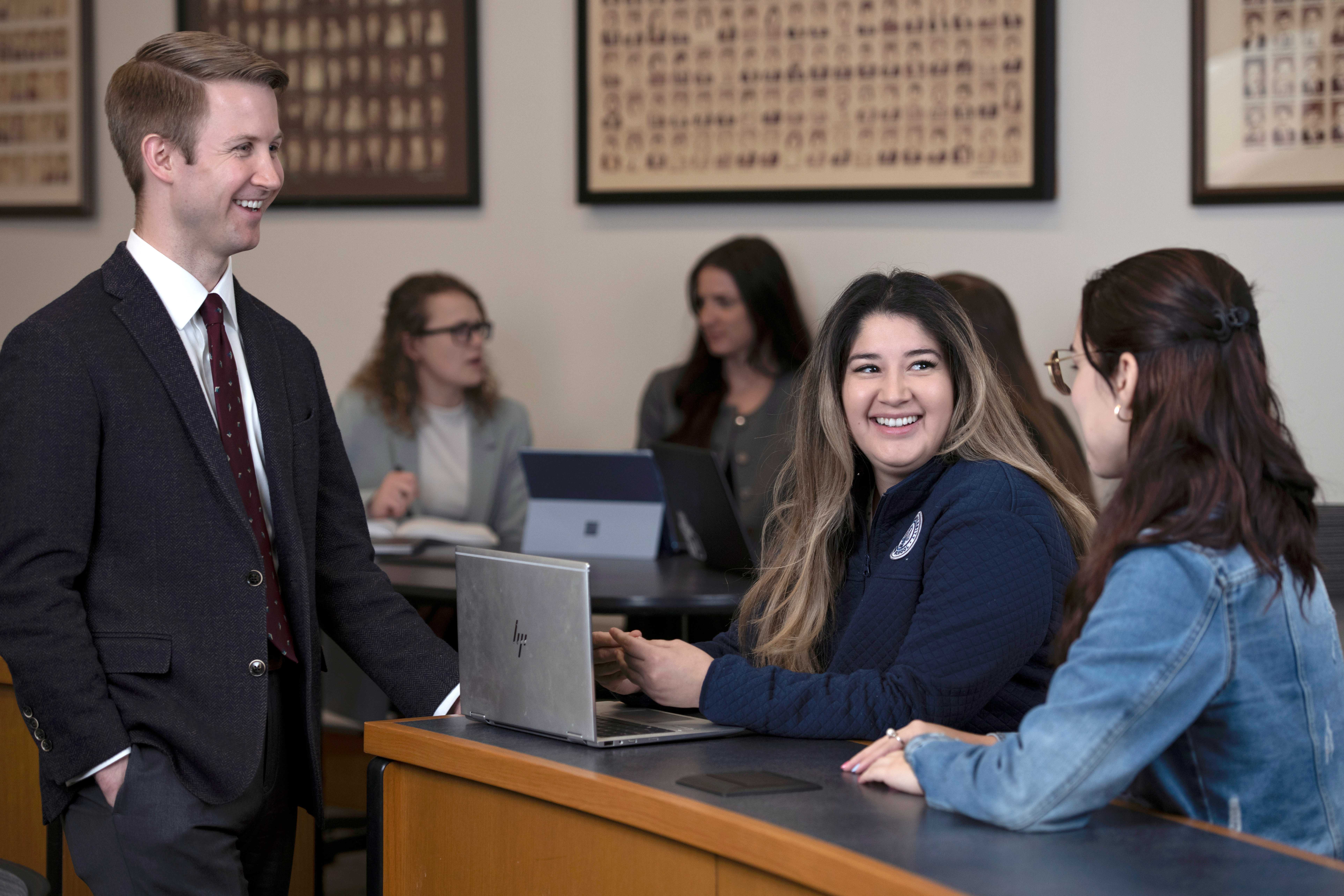 Students from Drake's Law, Politics, and Society program gather around laptops in a classroom to discuss an assignment