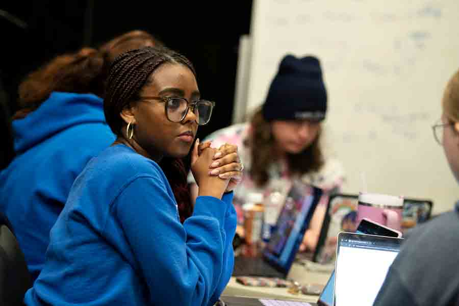 Students from Drake's Magazine and Brand Media program gather around a table to listen to capstone presentations