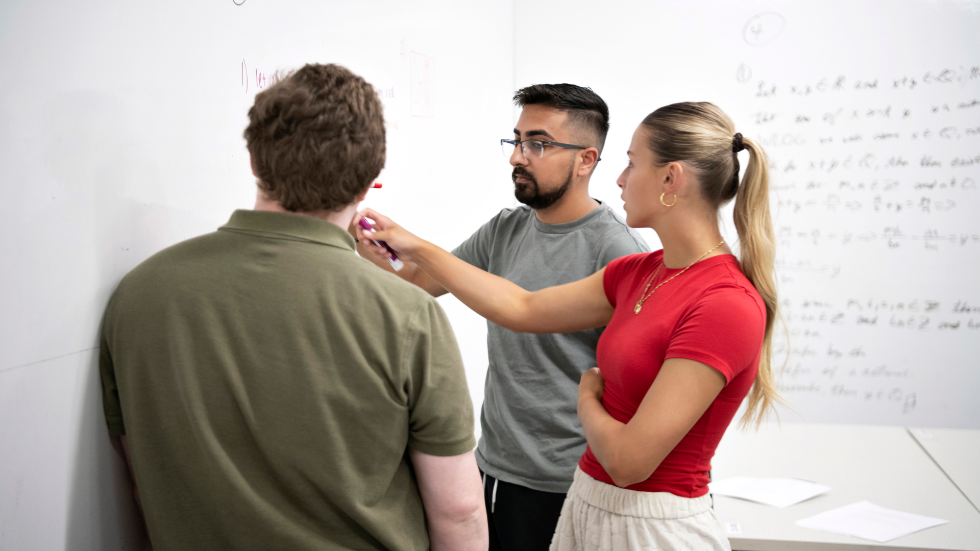 A faculty member explains an equation written on a whiteboard to two Mathematics Majors at Drake
