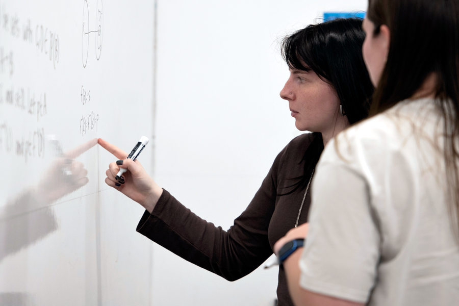 A Drake Mathematics student points to a whiteboard to explain how they solved a complex equation