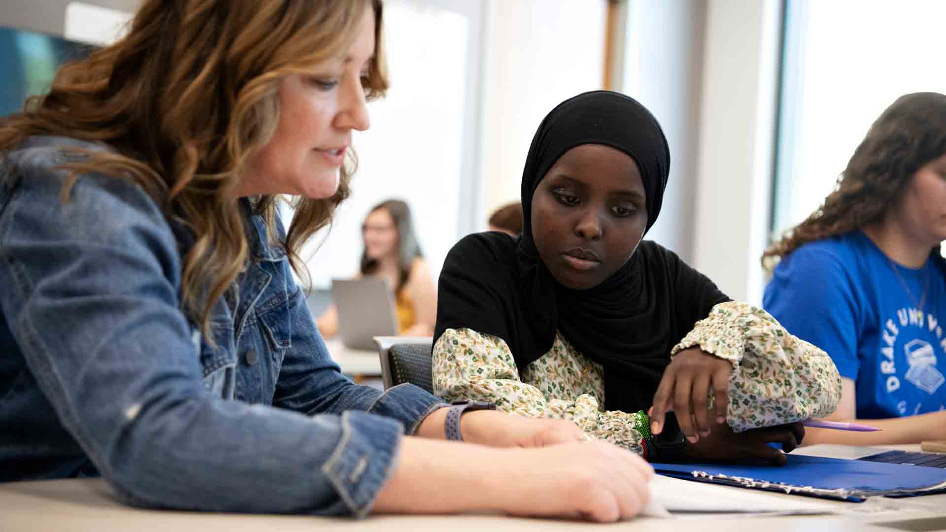 A Drake professor meets with a Mathematics for Secondary Education major in a common area to discuss an assignment