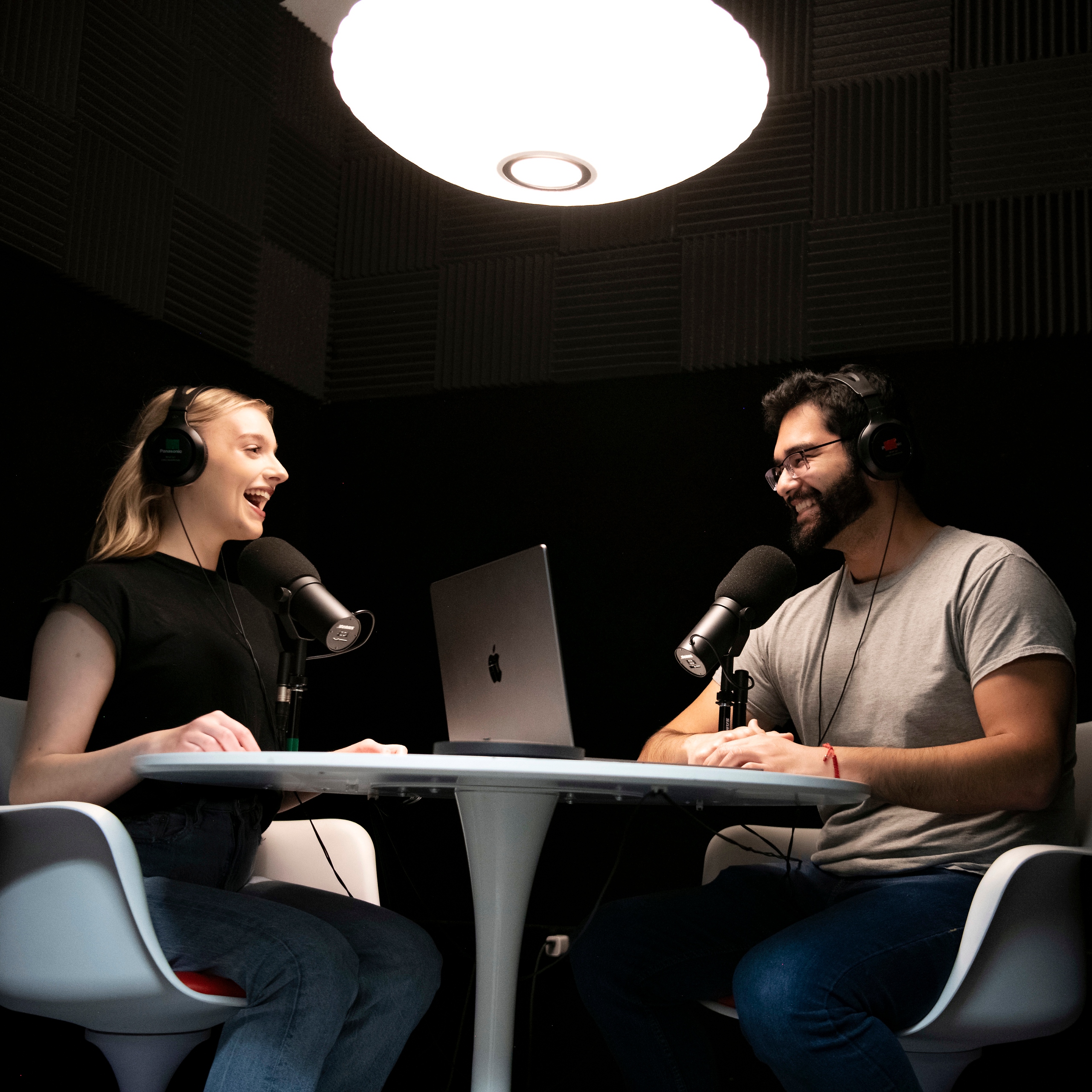 Two students from Drake's Multimedia Journalism Major practice podcasting techniques around a table