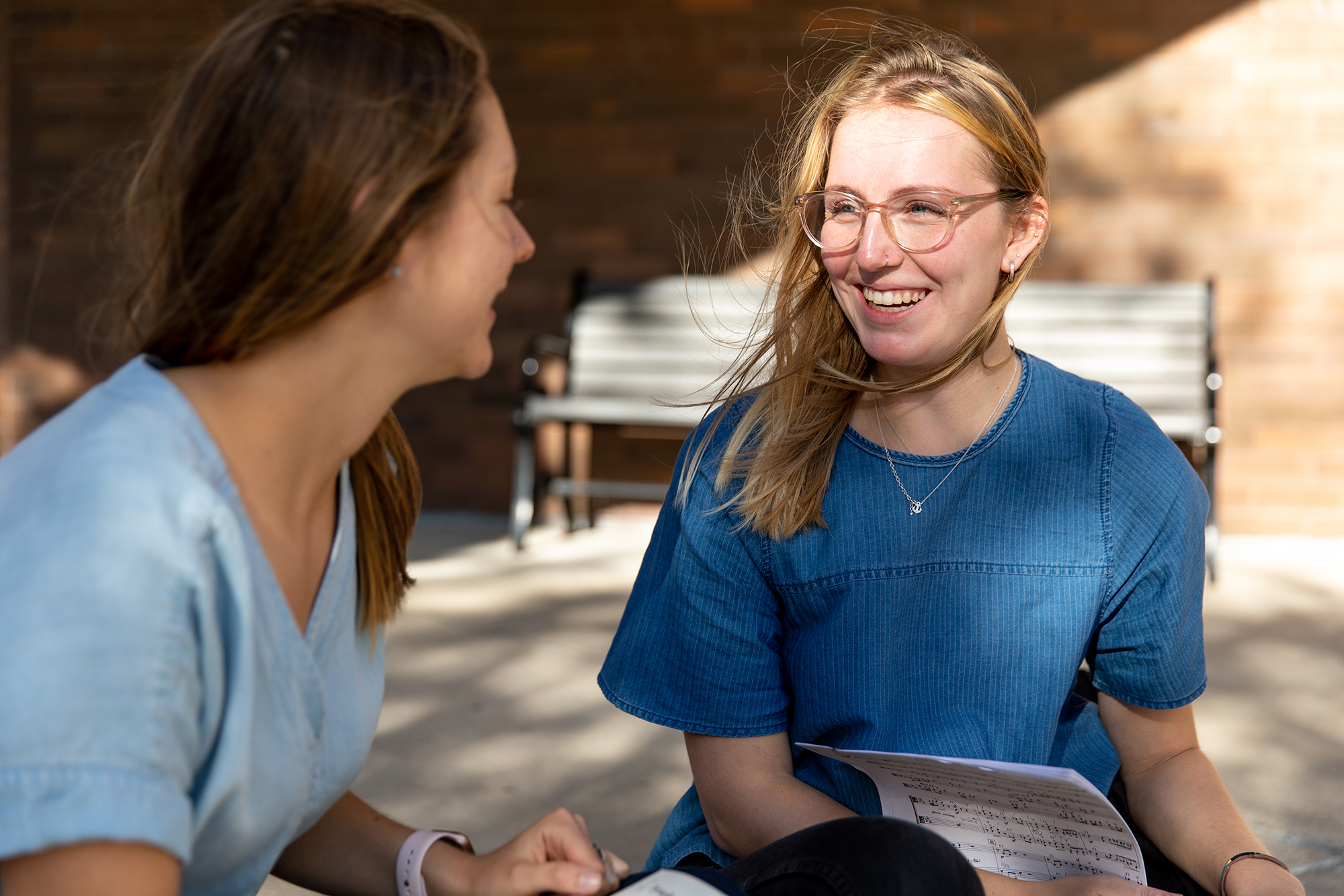 Two Drake students, one holding sheet music, converse outdoor about Music Education careers