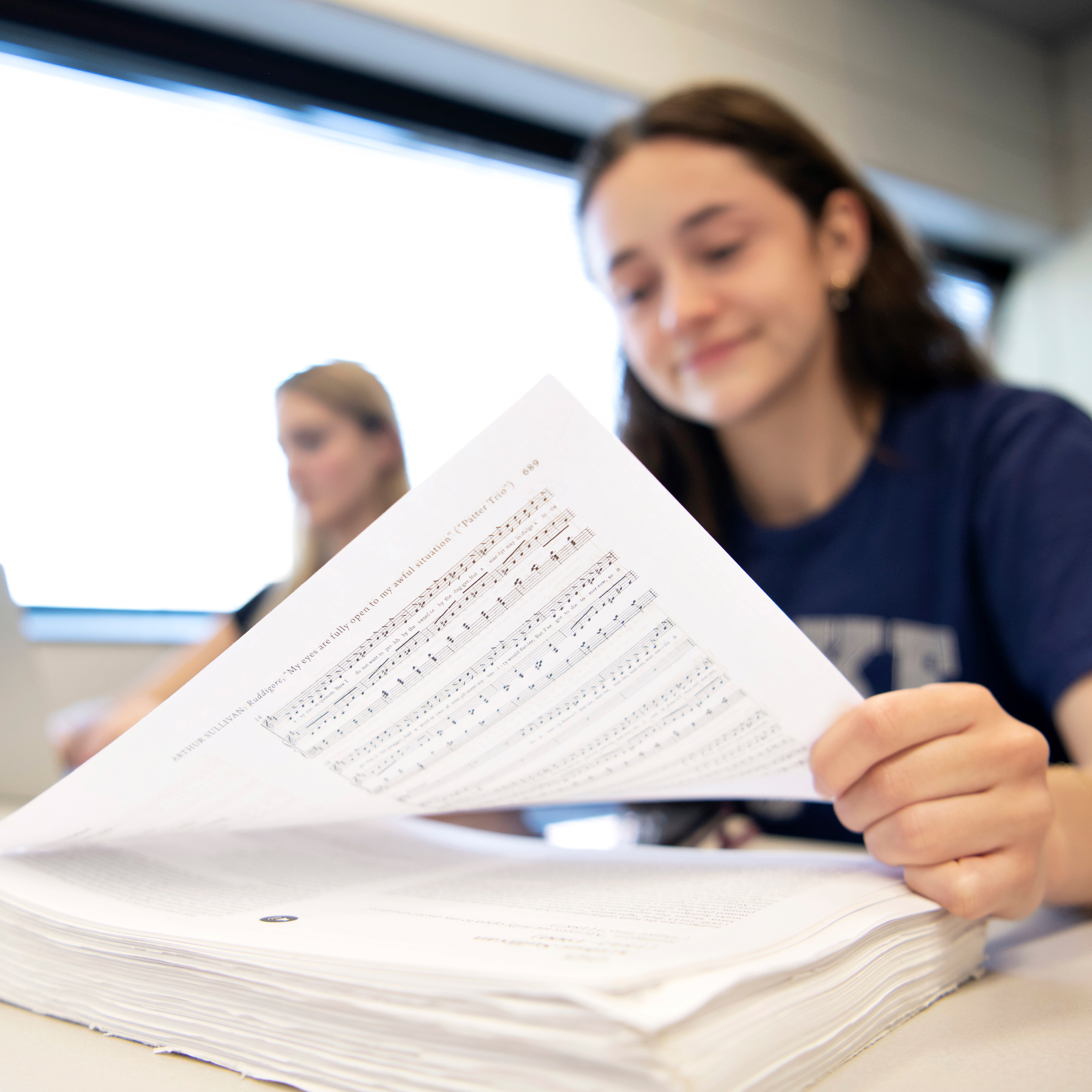 A student from Drake's Music Education program reviews sheet music stacked on a desk