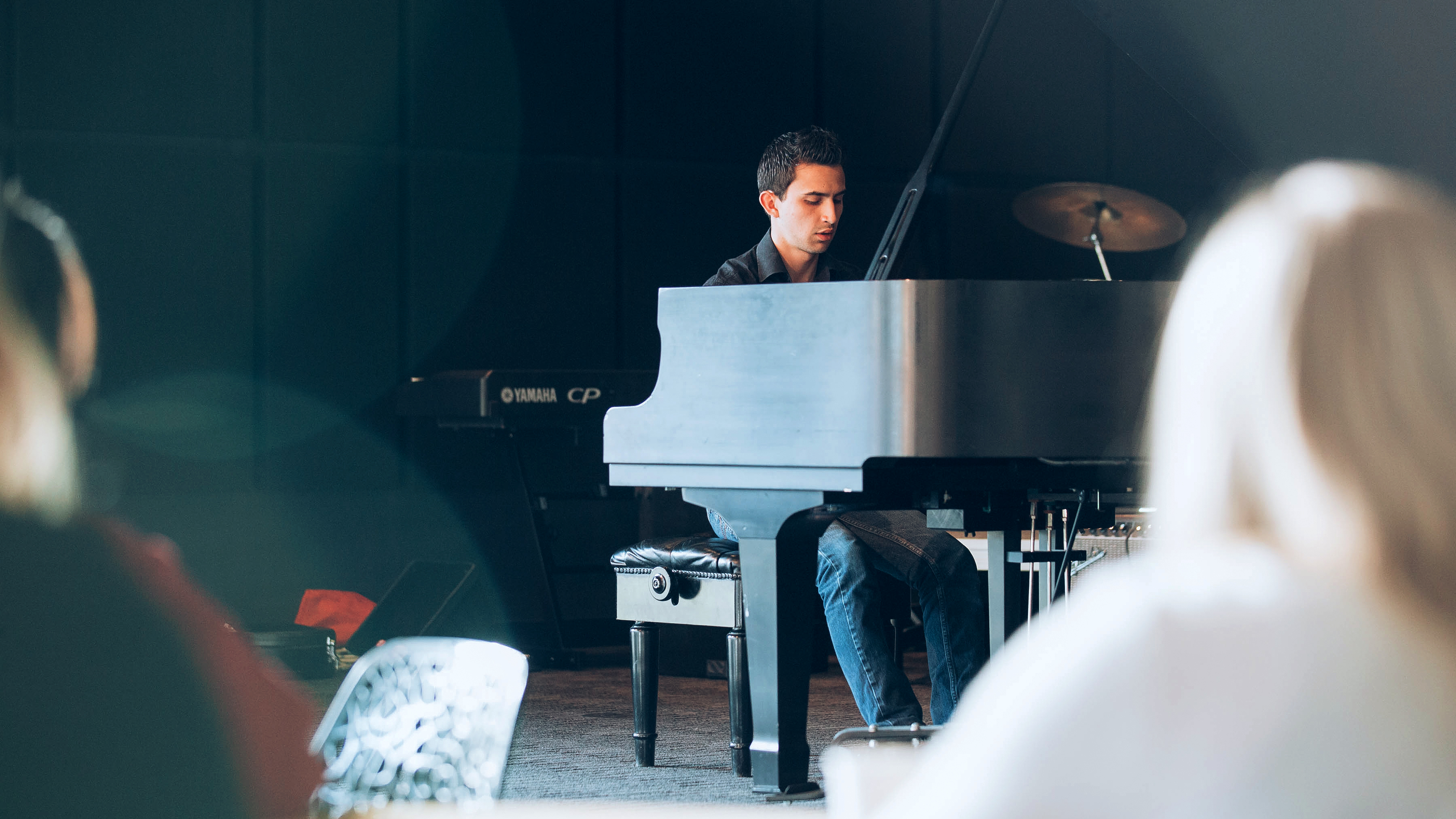 A Drake Music Education major plays a grand piano for an audience of fellow students