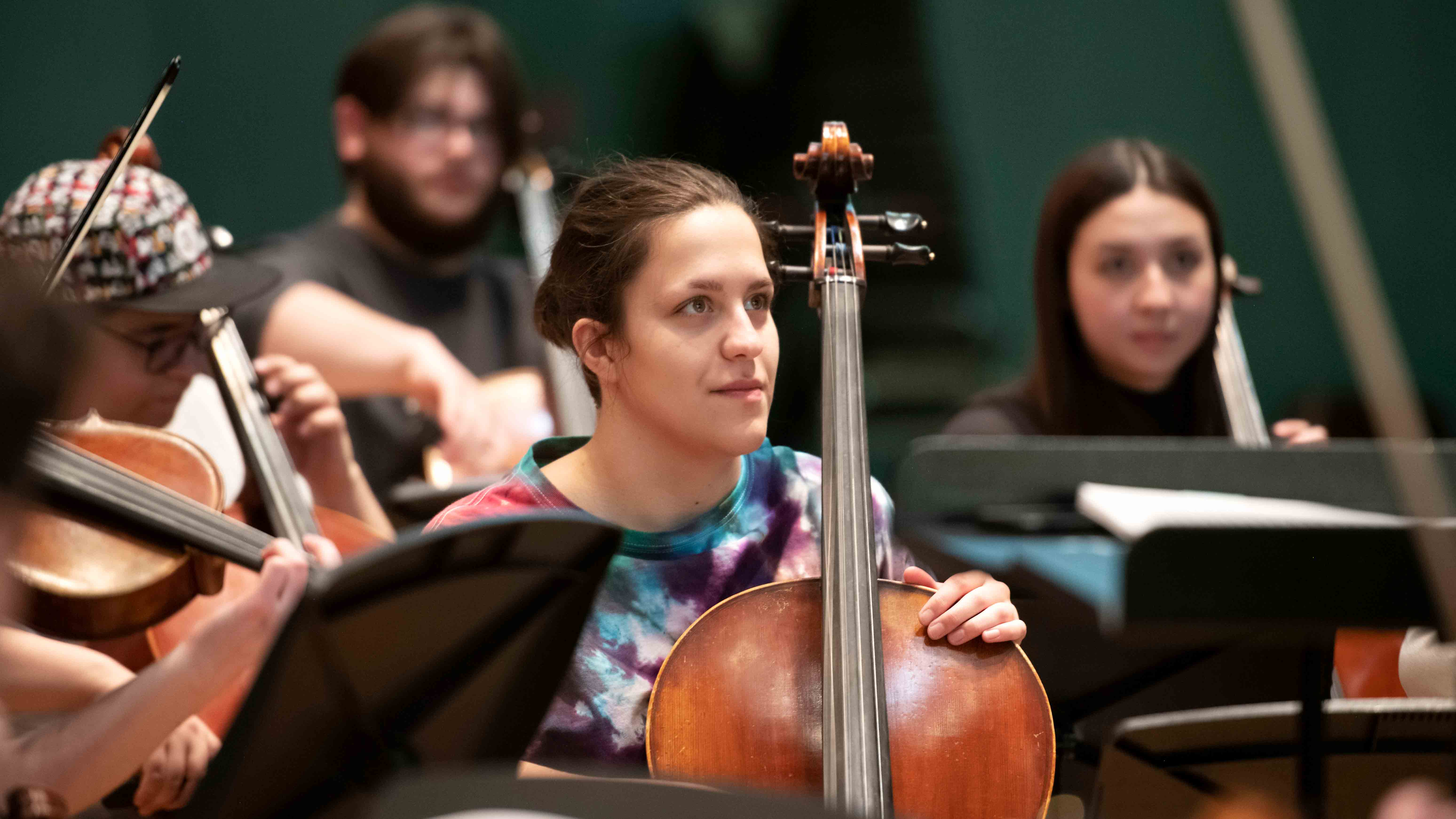 A Drake Cello major listens to the conductor's feedback during a rehearsal
