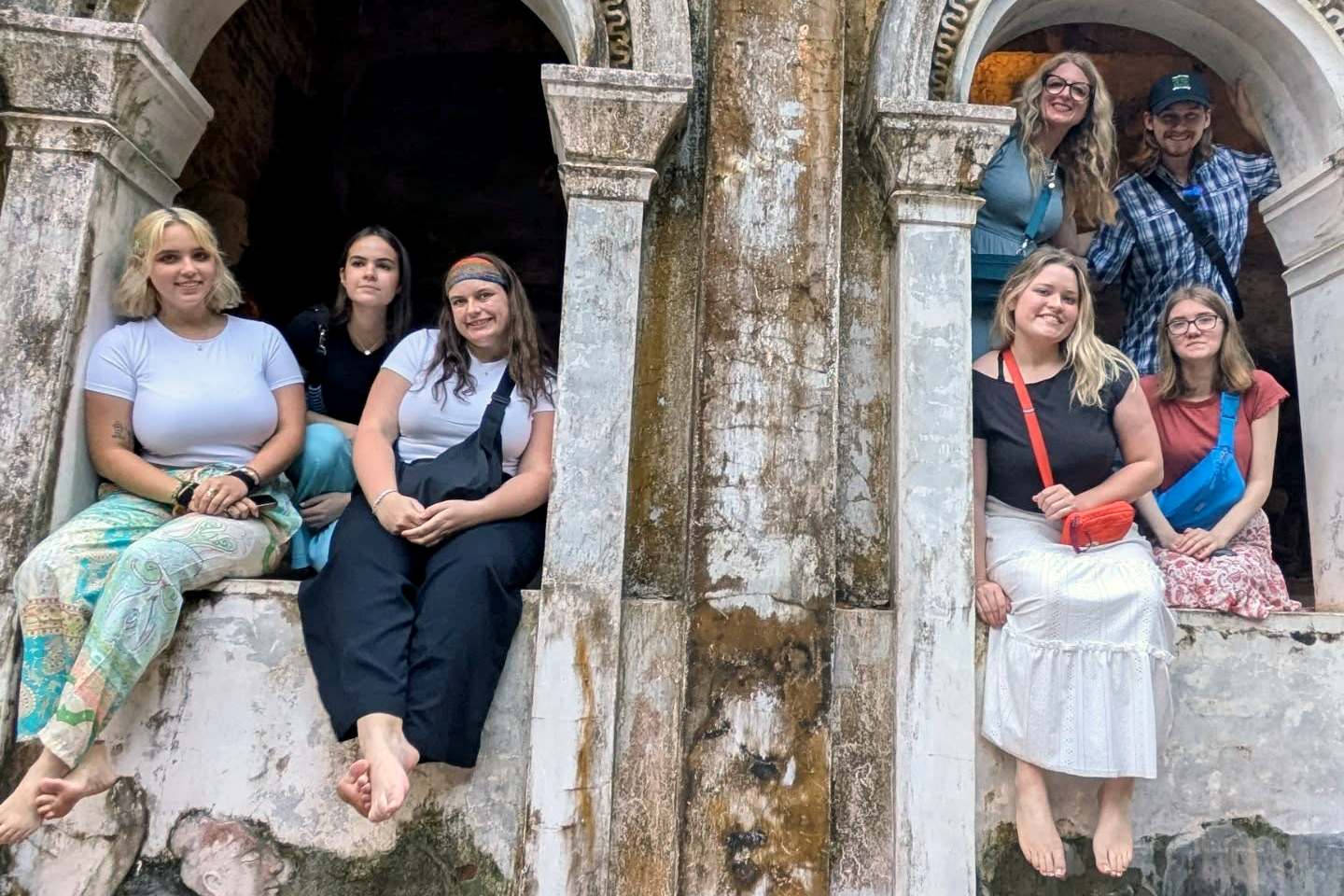 A group of Drake students pose among an old building's arches during a study abroad trip