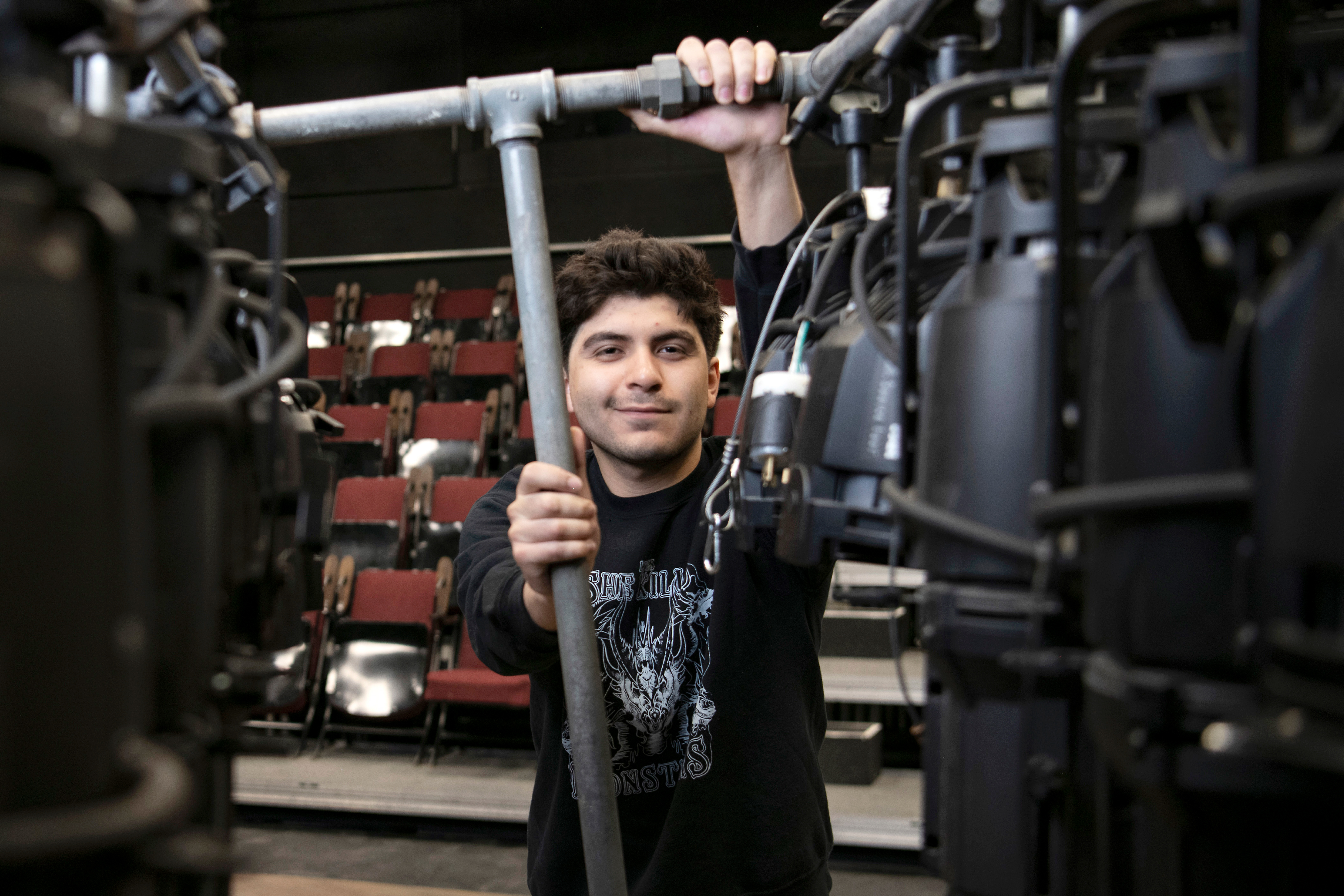 A student from Drake's Musical Theatre program holds a rig supporting a lighting setup from backstage