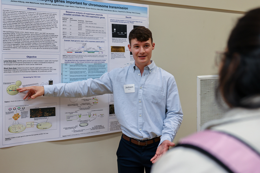 During Drake's annual DUCURS event, a Neuroscience Major describes their research to an audience, pointing to a poster board