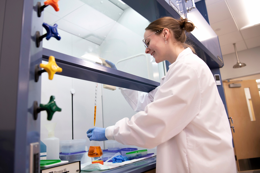 In a campus laboratory environment, a Neuroscience student at Drake practices measuring fluids with a beaker and a test tube