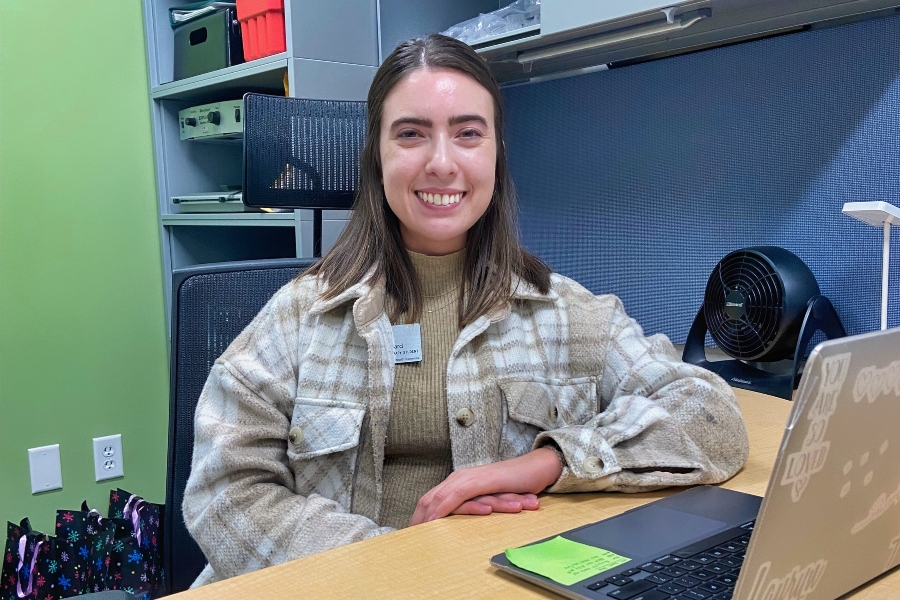 From behind a laptop, a Drake OTD student smiles while working on their capstone project