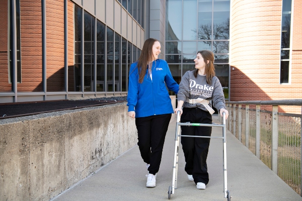Two Drake OTD students, one with a walker, practice getting around campus with assistive devices