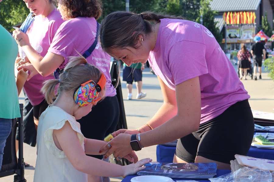 At an outdoor event, a Drake OTD student assists a child wearing hearing protection