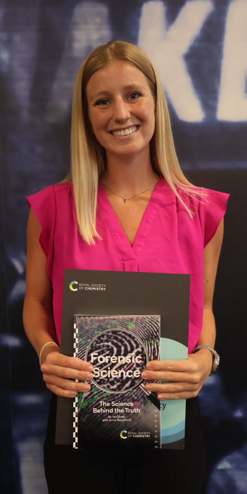 Drake Doctor of Pharmacy alum Anna Braun, PharmD’25, holds a forensic science textbook