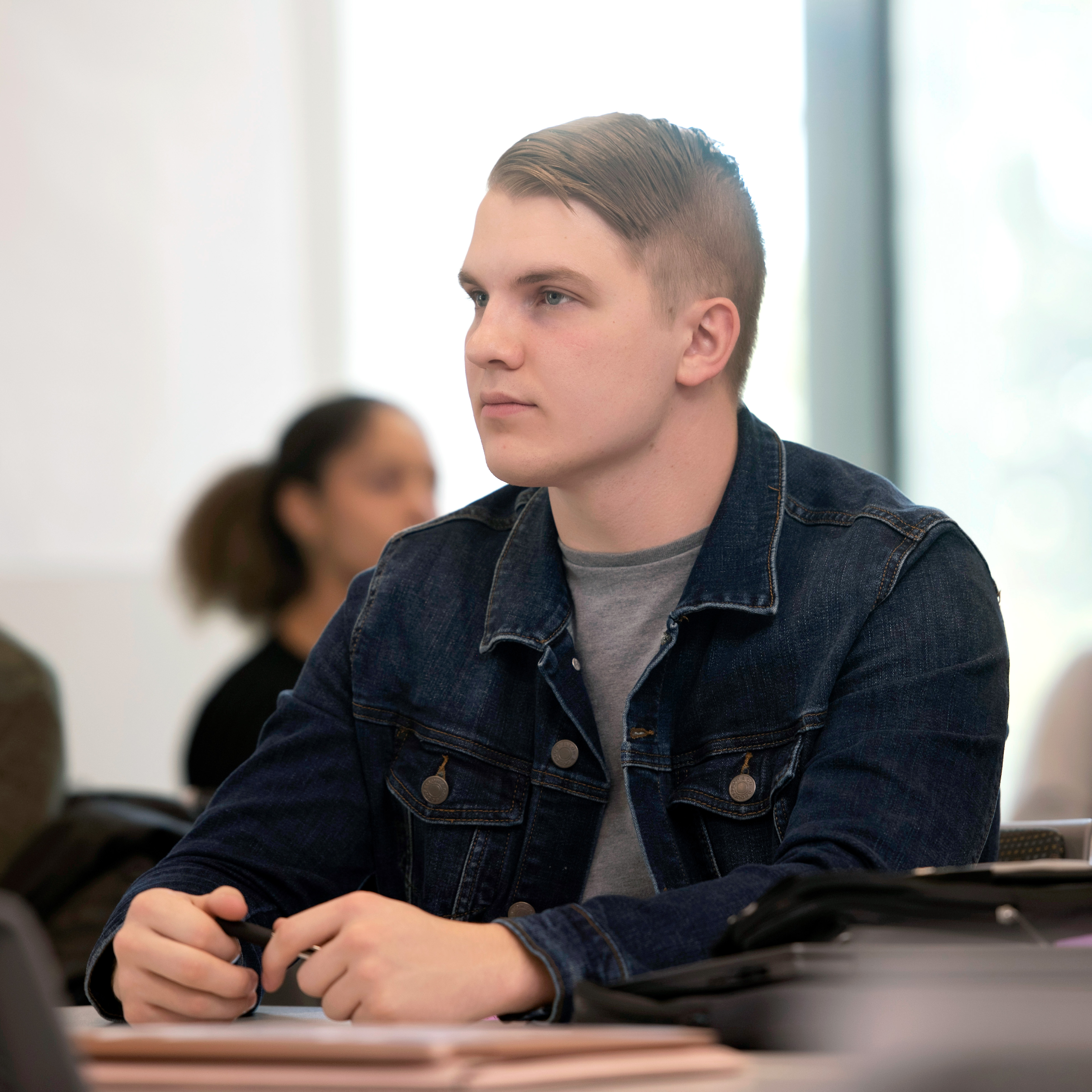 A Drake Philosophy student behind a desk listens during a class lecture