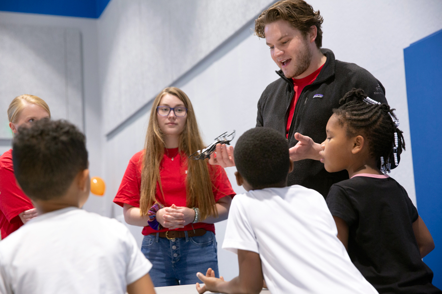 At STEM Day, a Drake Physics discusses the properties of a metal device to a group of elementary-age students