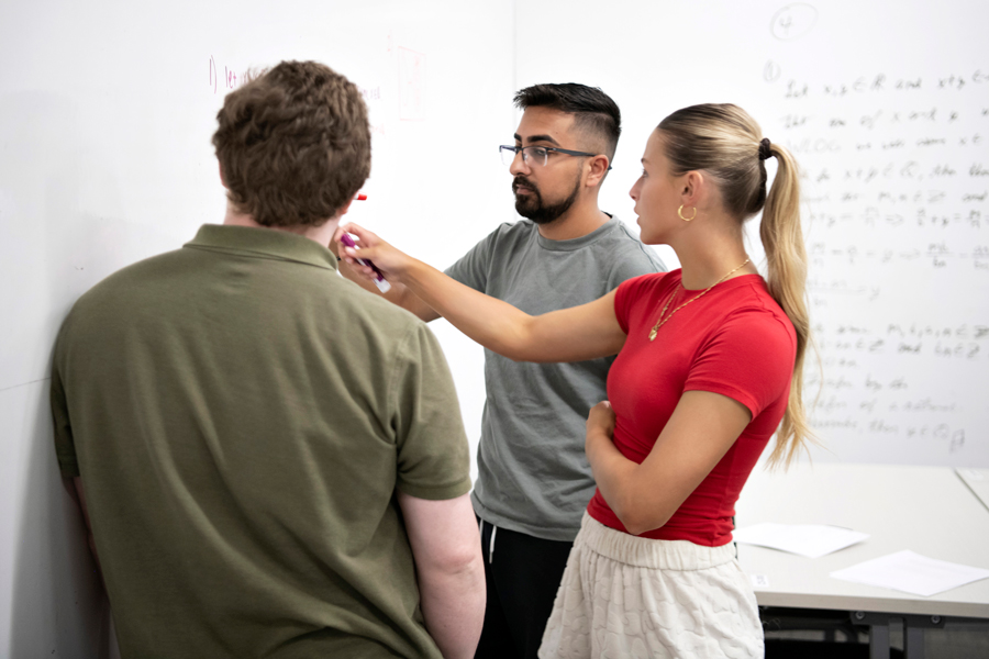 A group of Drake Physics students tackle an equation written on a white board
