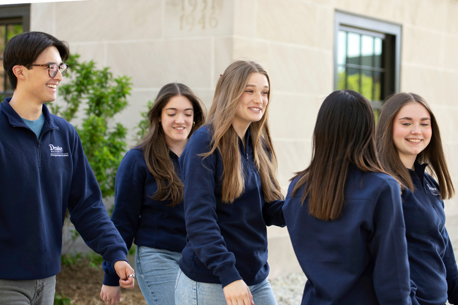 A group of Drake Politics students walks outdoors, wearing navy blue sweatshirts
