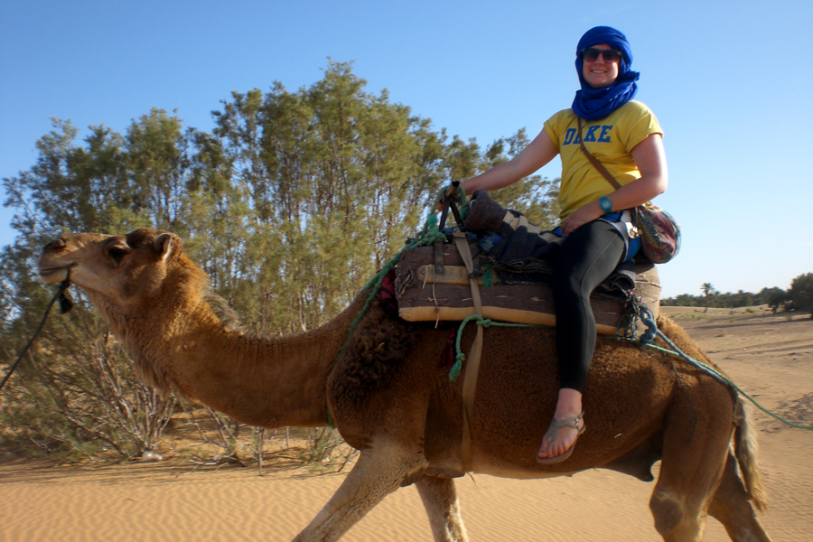 A Drake Politics student rides a camel in a desert environment on a study abroad trip