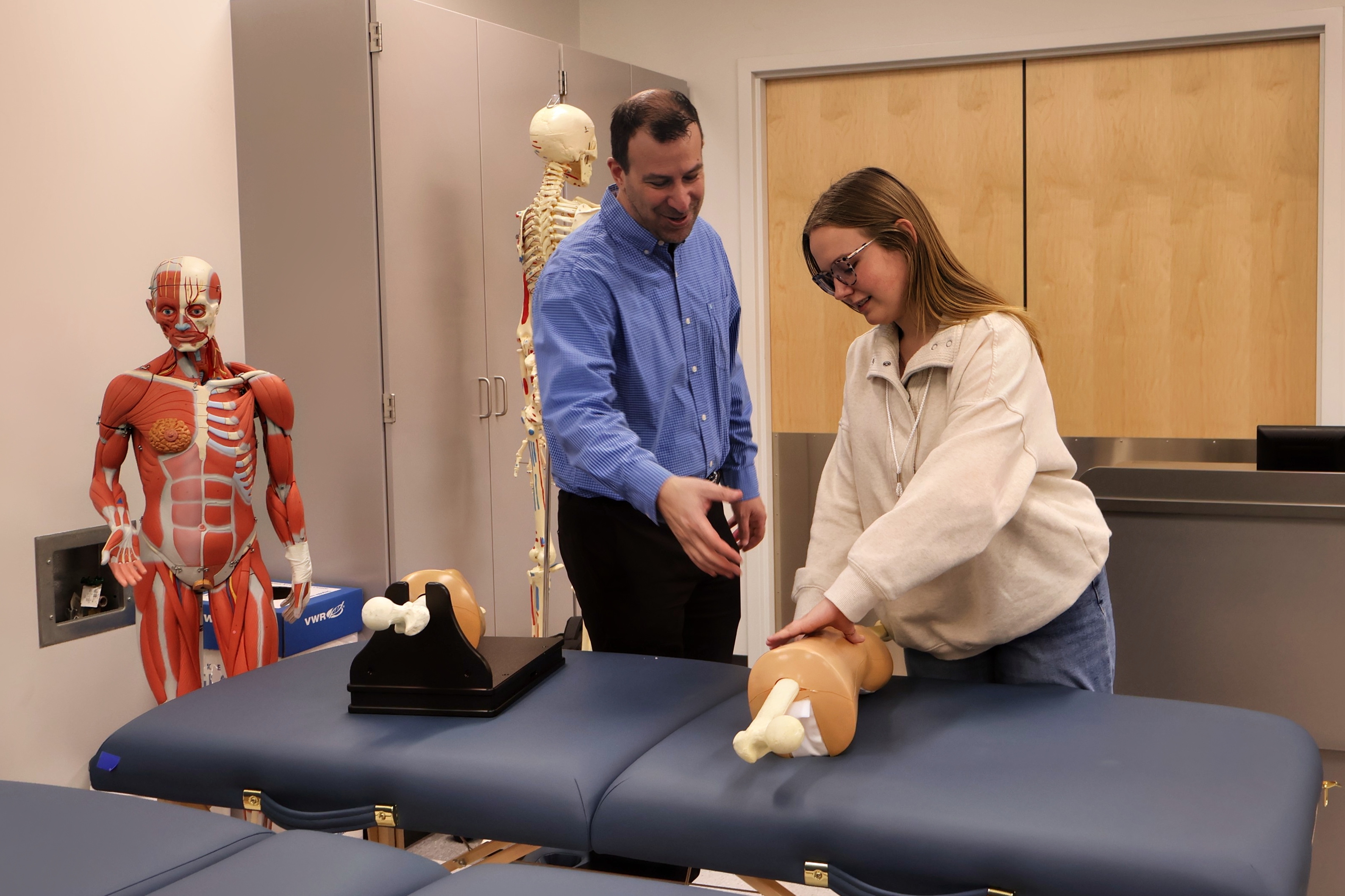 In a simulation lab, a Drake faculty member instructs a Pre-Athletic Training student in performing a rehabilitative therapy