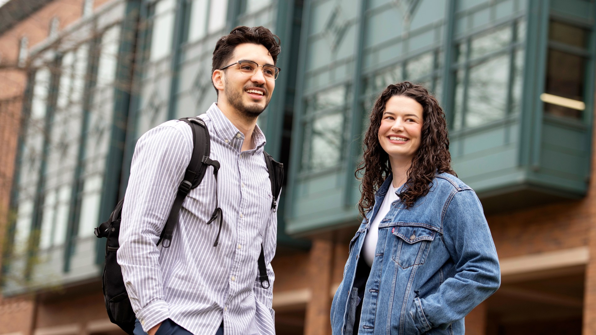 Two Drake Pre-Law students turn to each other in conversation while outside a red brick classroom building
