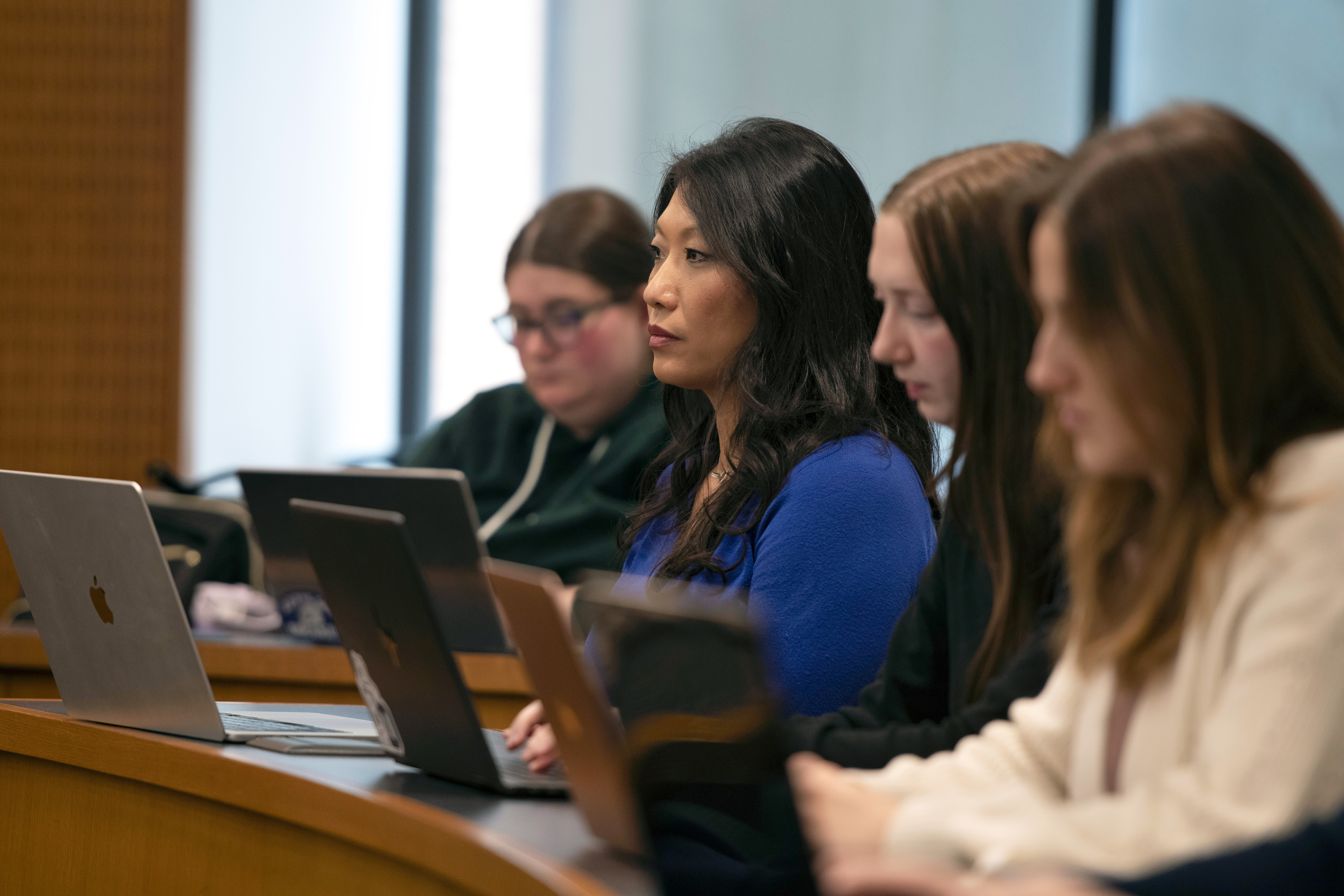 Drake Pre-Law students sitting at a long desk study information on their laptops and tablets