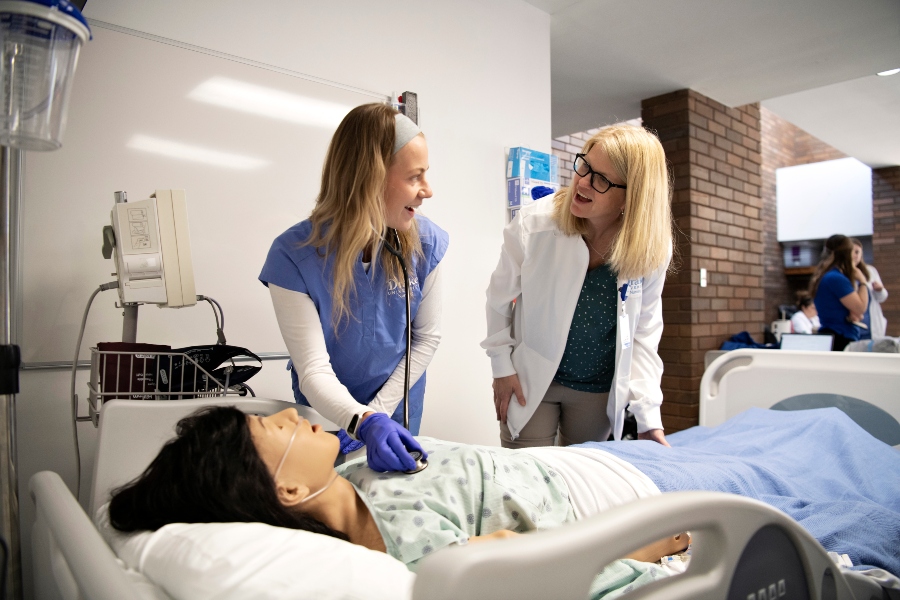 An instructor guides a Pre-Med student's use of a manikin in one of Drake's simulation labs