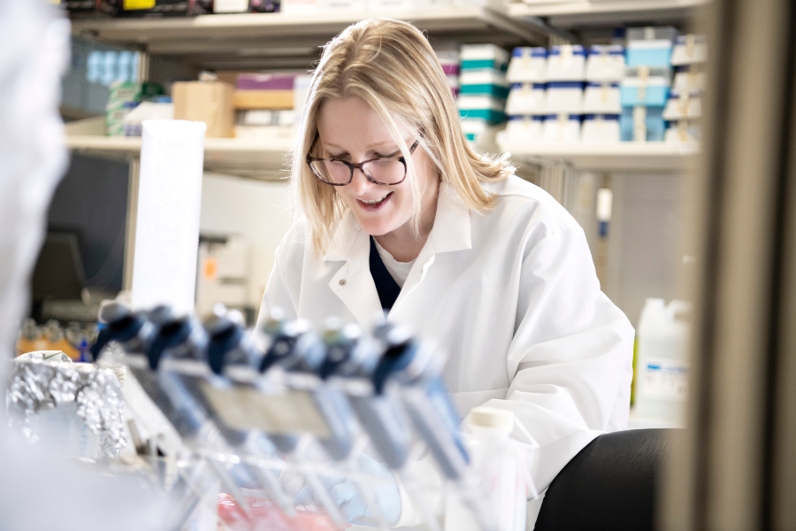 A Drake Pre-Medical Student wearing a lab coat works on a project in a campus lab