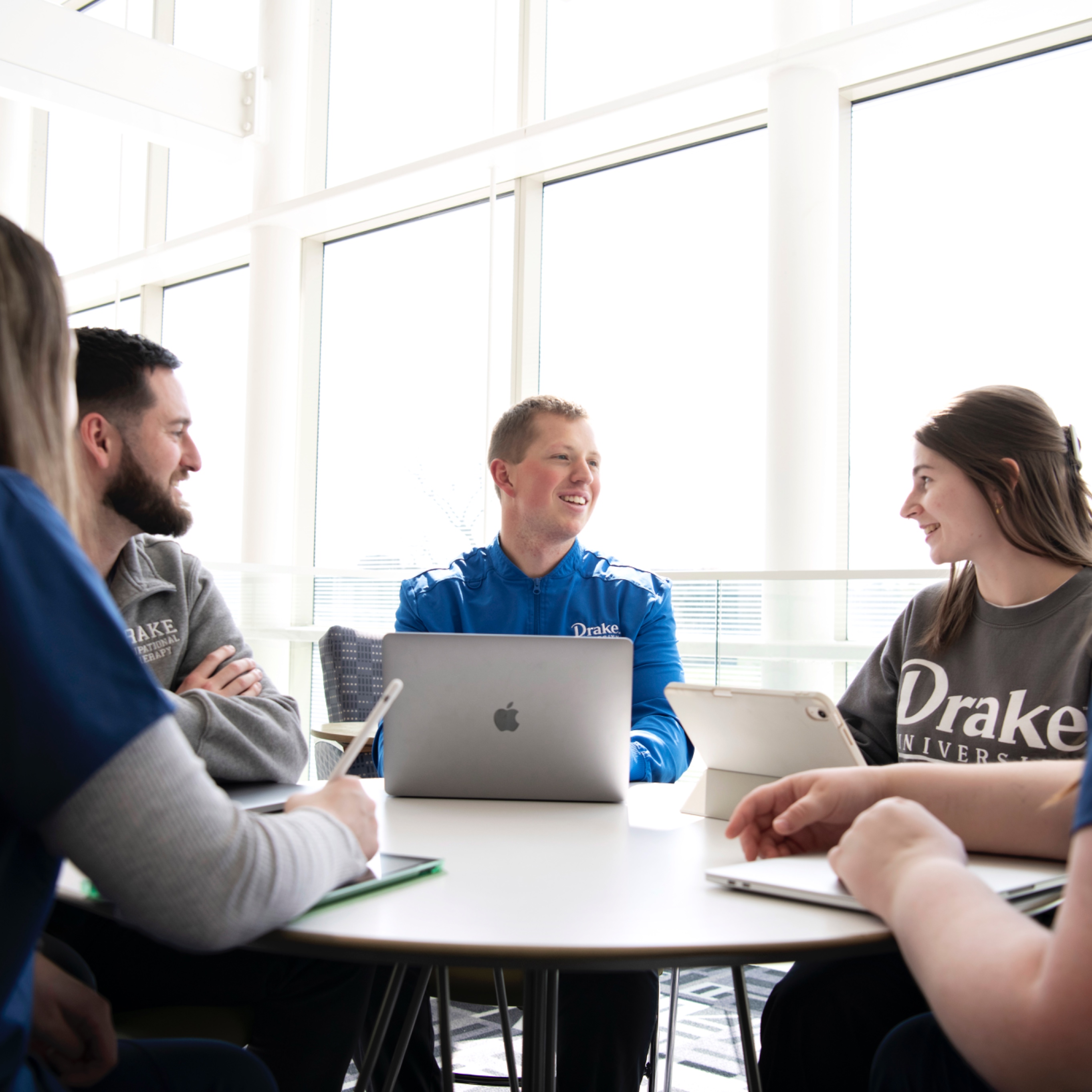 Drake Pre-Occupational Therapy students hold a study session with laptops around a table in a common area with large windows
