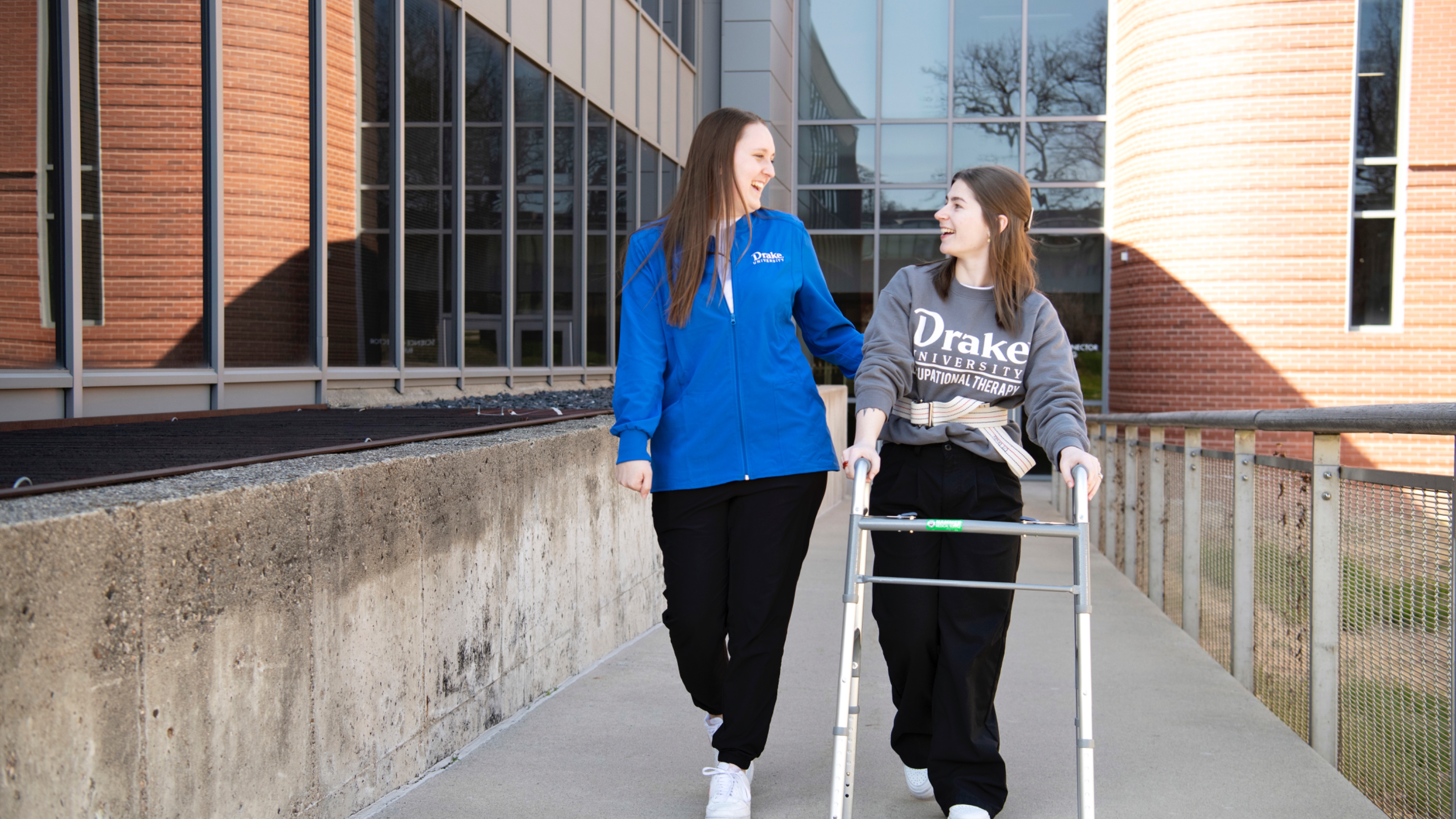 Two Drake Pre-Occupational Therapy students practice using assistive devices around campus