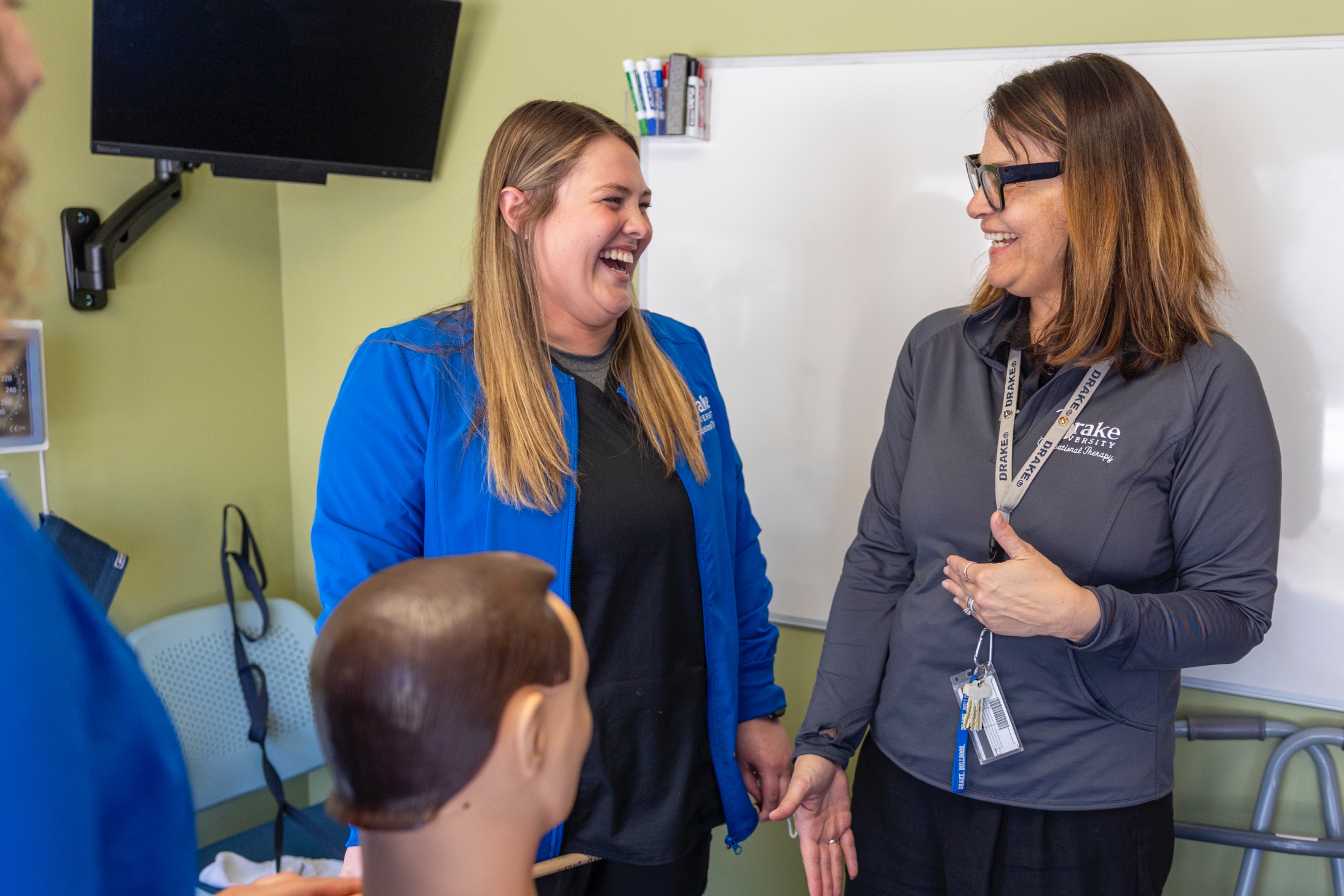 A Drake Pre-Occupational Therapy student learns to assist patients from a faculty mentor in a simulation classroom