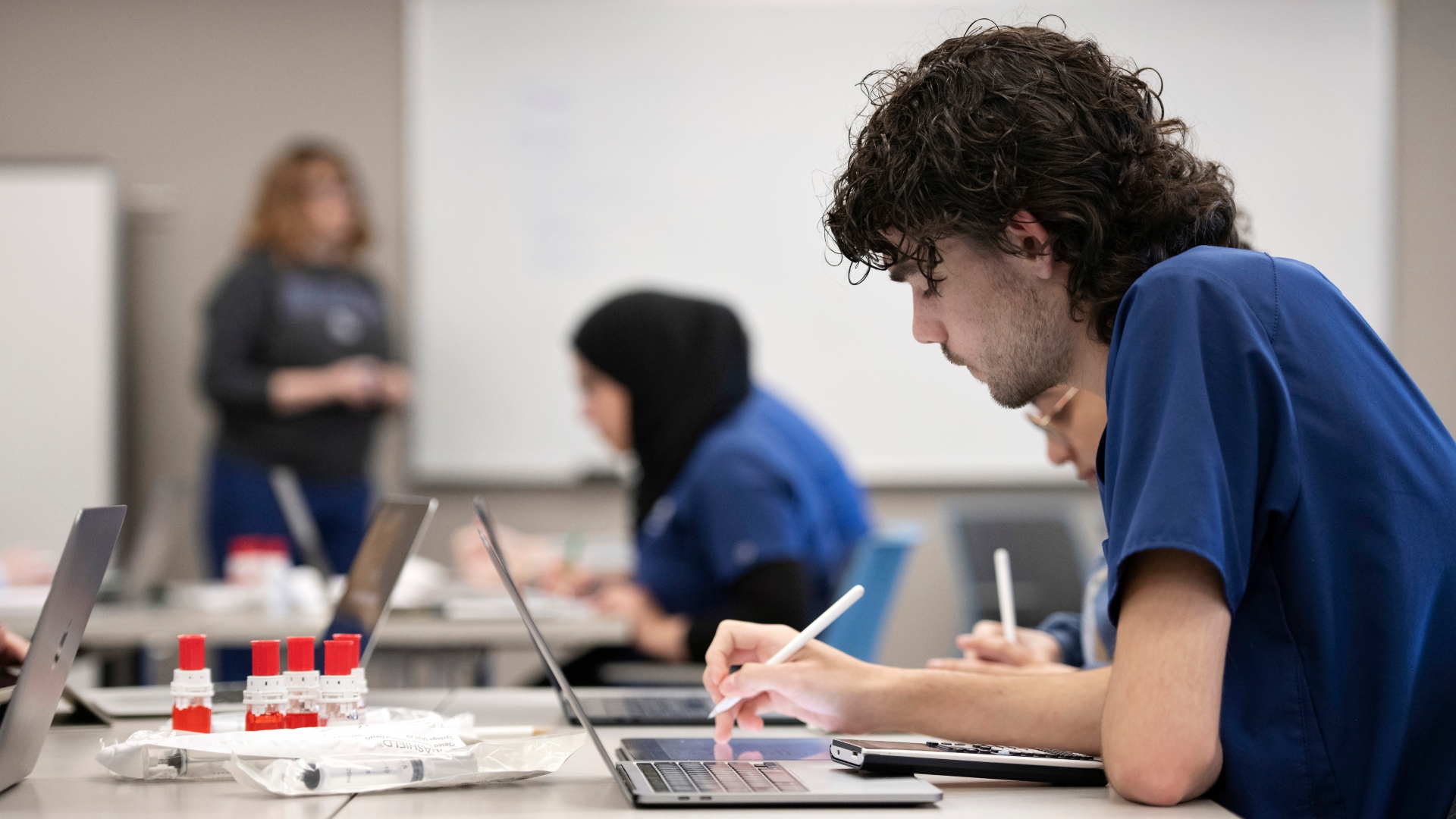 A Drake Pre-Pharmacy student records data onto their laptop in a laboratory classroom