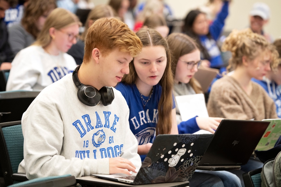Drake Pre-Pharmacy students discuss their notes from behind laptops in a lecture hall