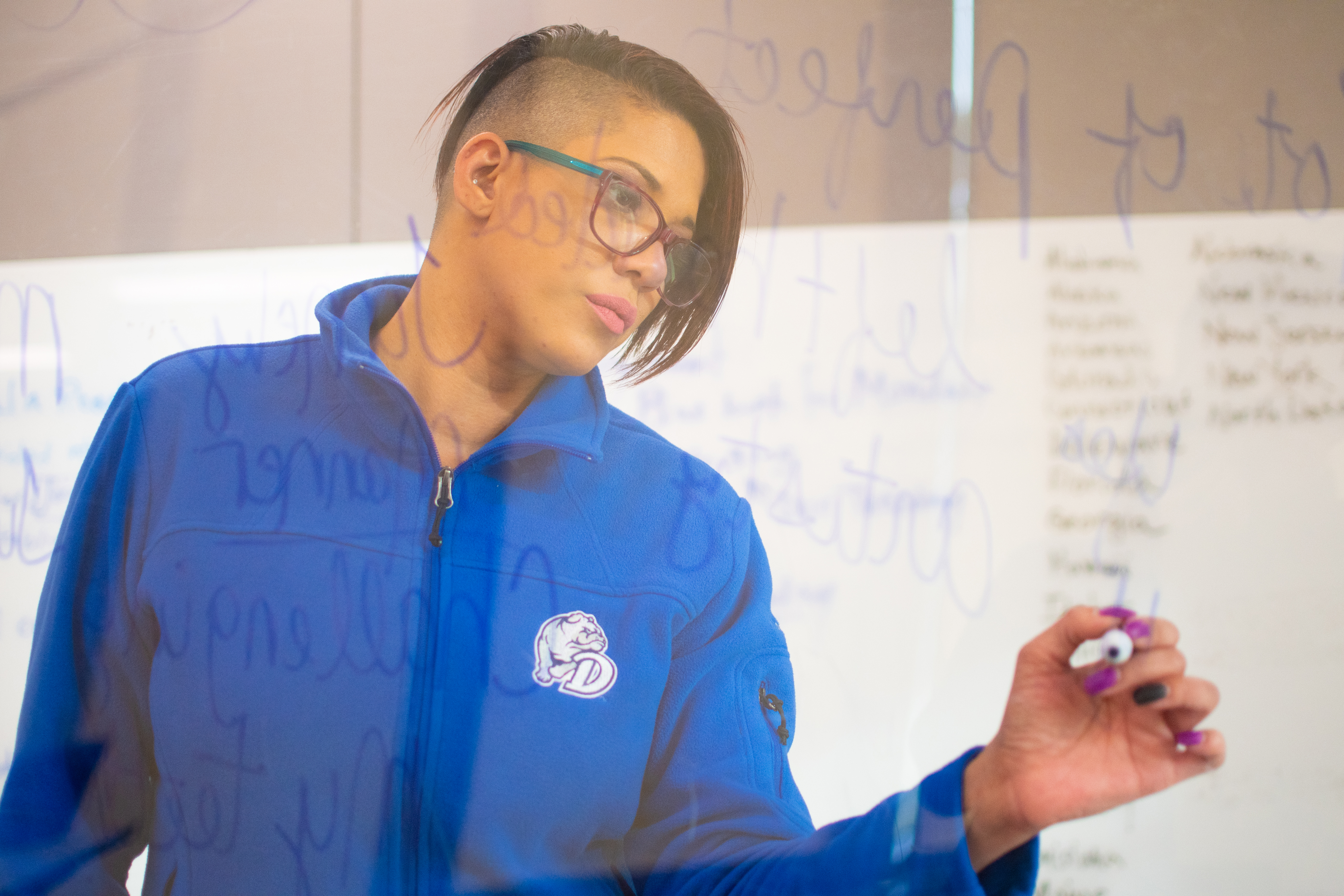 A Drake Psychology faculty member in a blue pullover writes observations for a research study on a clear surface