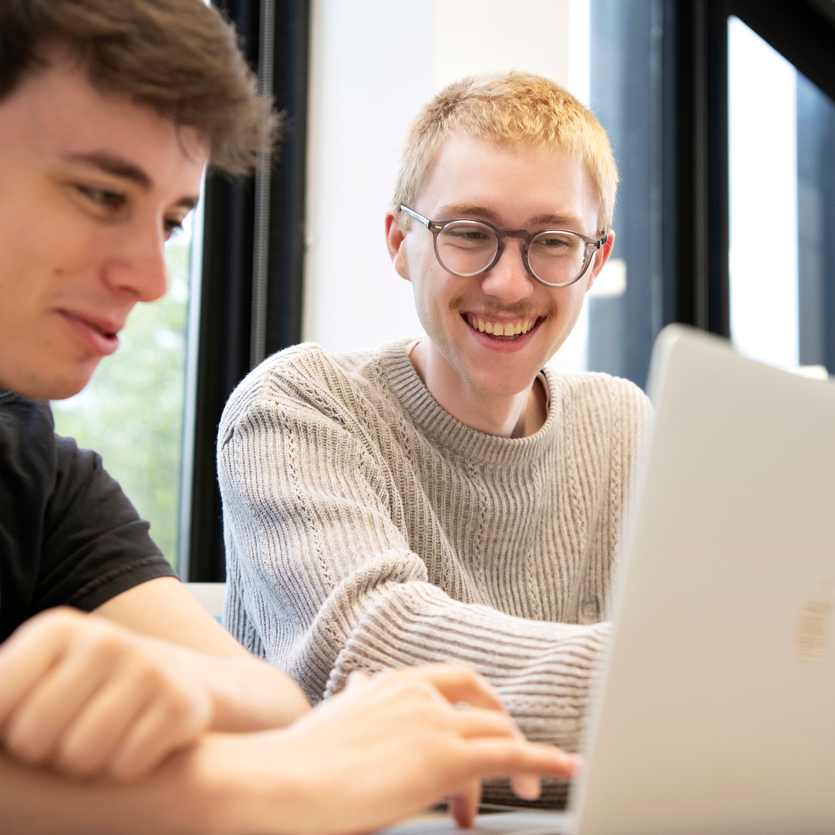 Two Drake Public Relations students focus on a project on a shared laptop