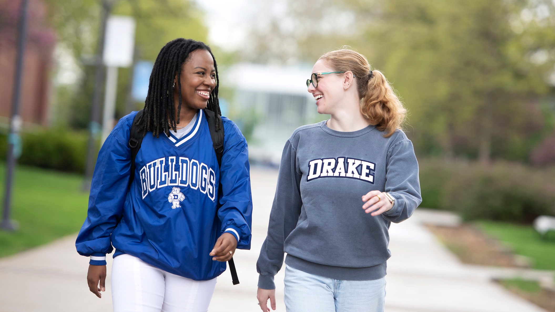Two Public Relations Majors wearing Drake sweatshirts smile as they casually venture through campus
