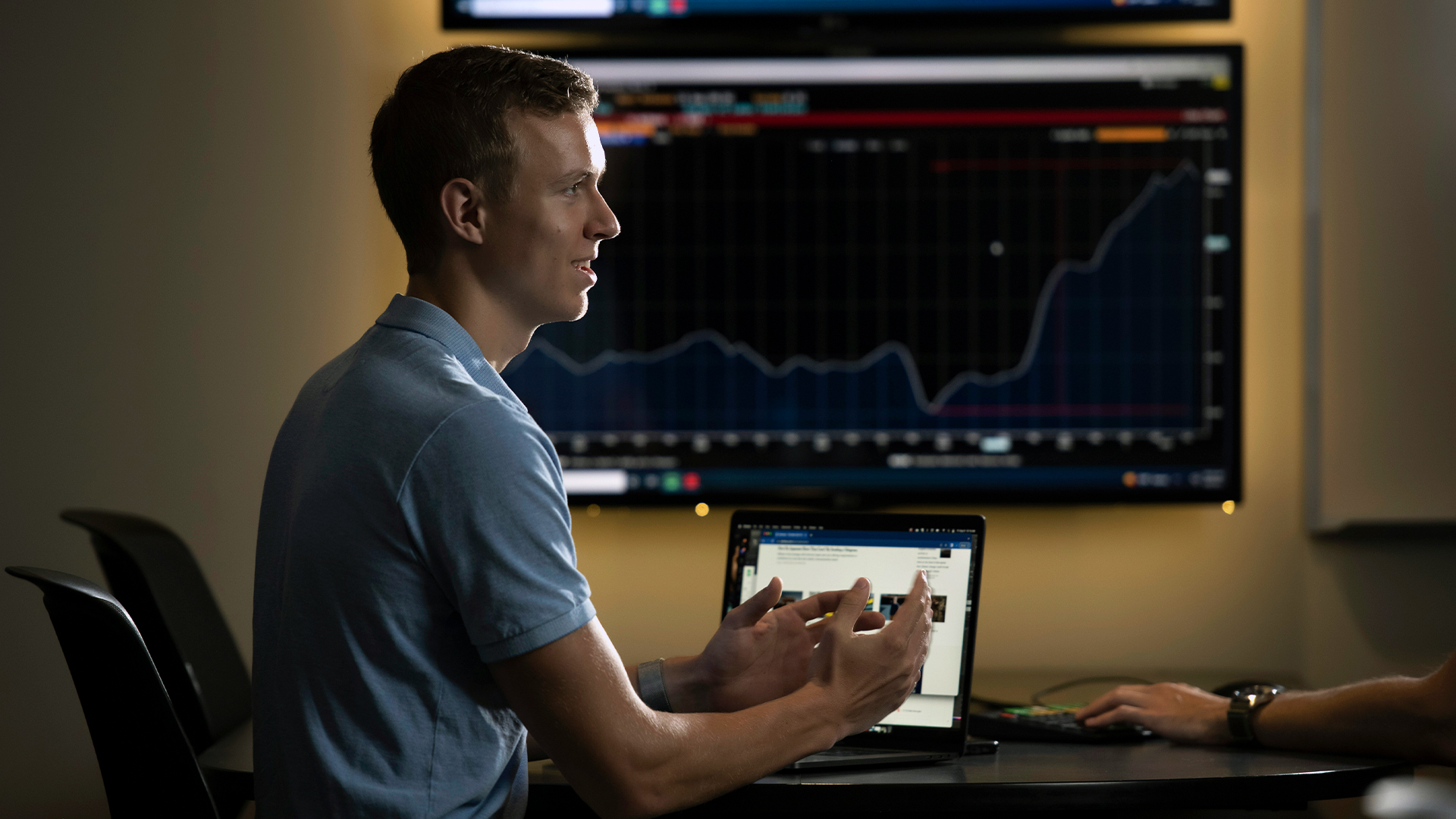 A Drake Quantitative Economics Major, sitting near a laptop and large monitor with a graph, describes their solution