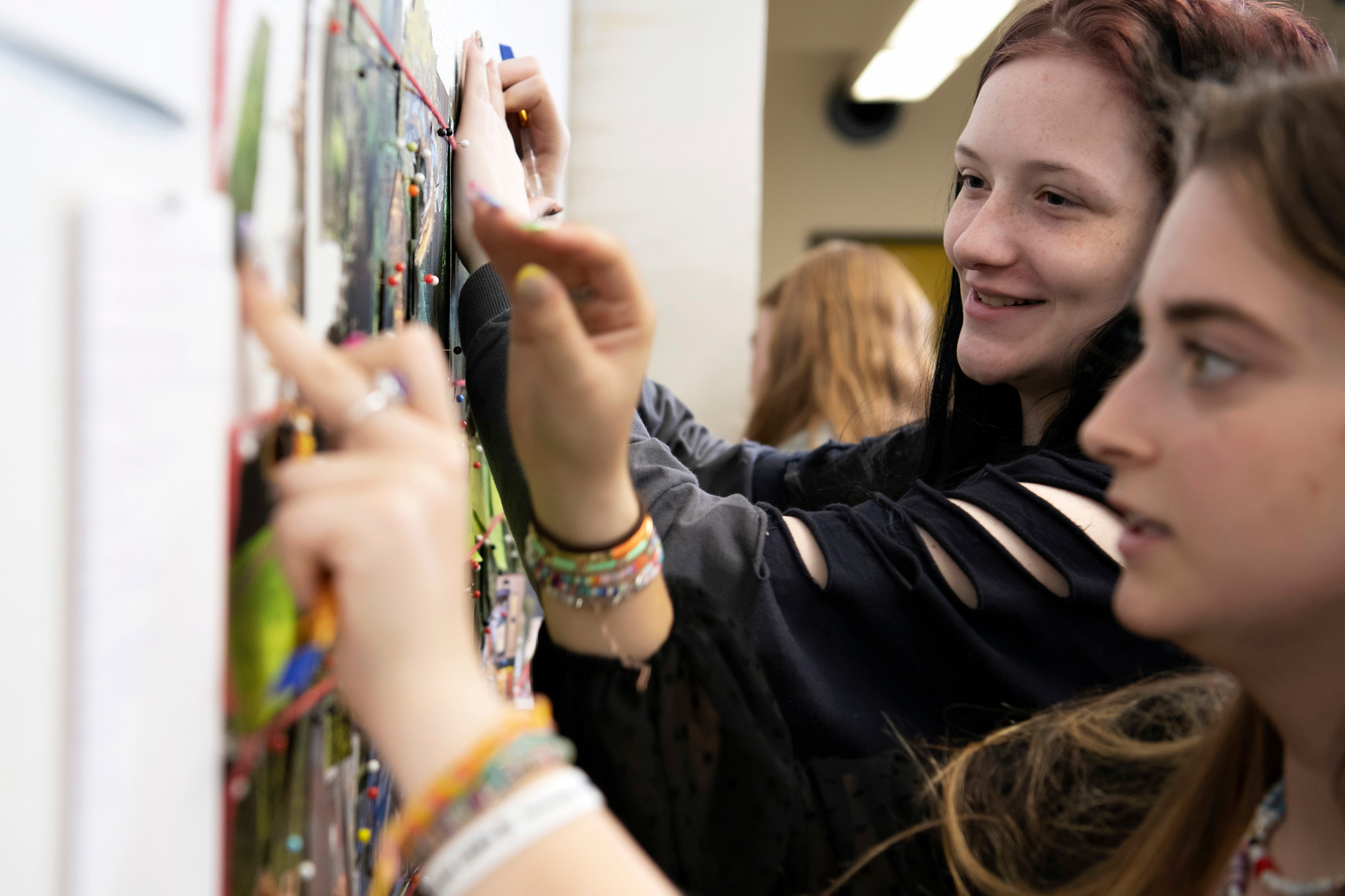 Drake Religious and Interfaith Studies students participating in a youth camp activity pin items to a board