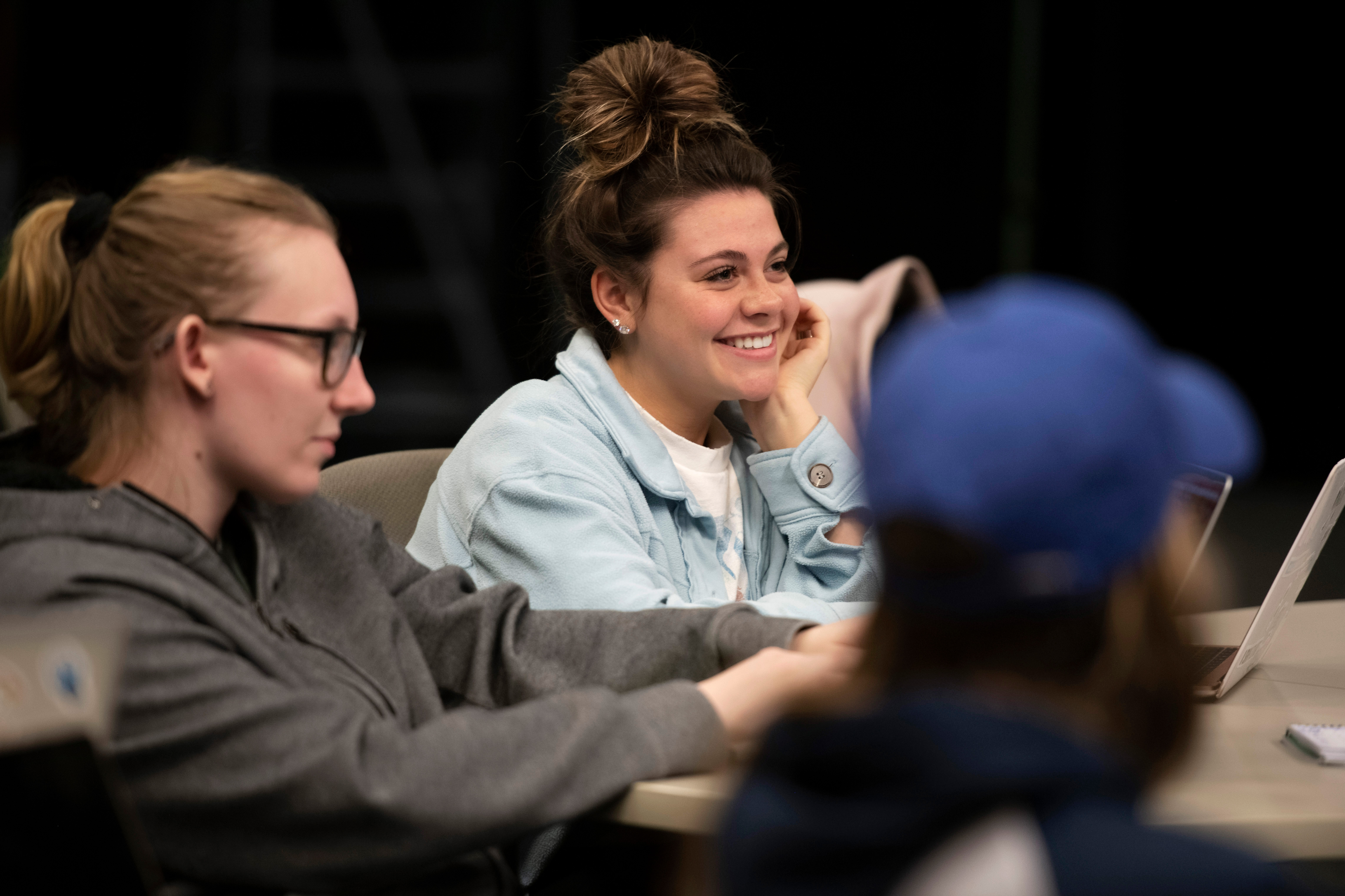 Drake Religious and Interfaith Studies students smile, lean, and listen during a classroom discussion around a table