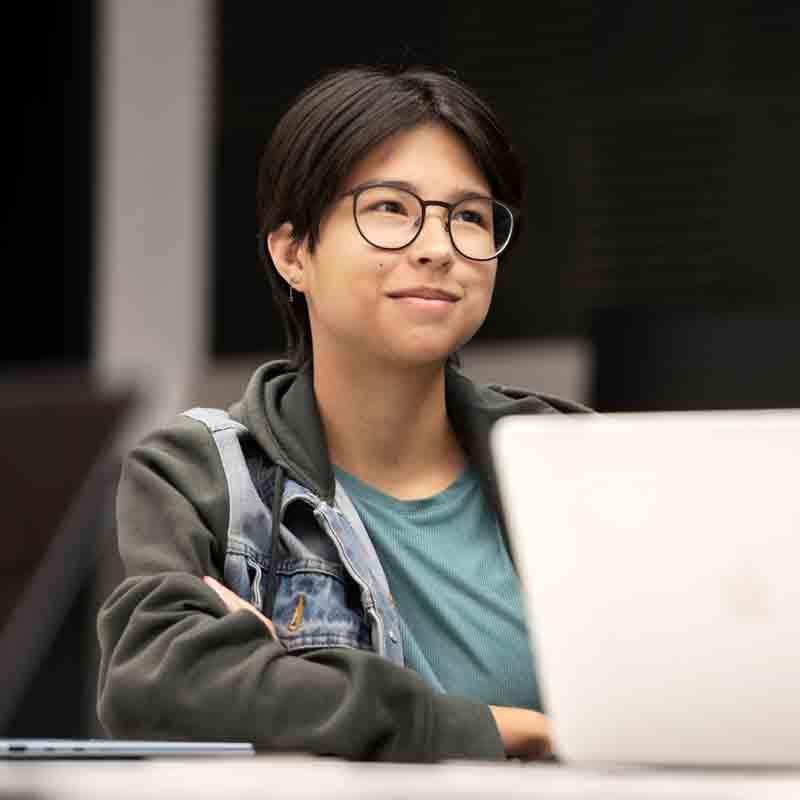A Drake Spanish major looks upward while sitting behind a classroom desk