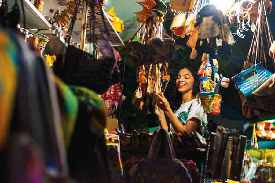 A student browses through a tightly packed shop with purses and other sundry items