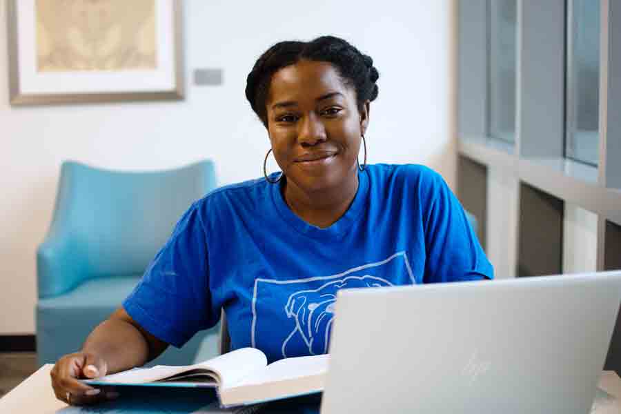 A Drake Spanish major works on a research assignment, textbook and laptop open
