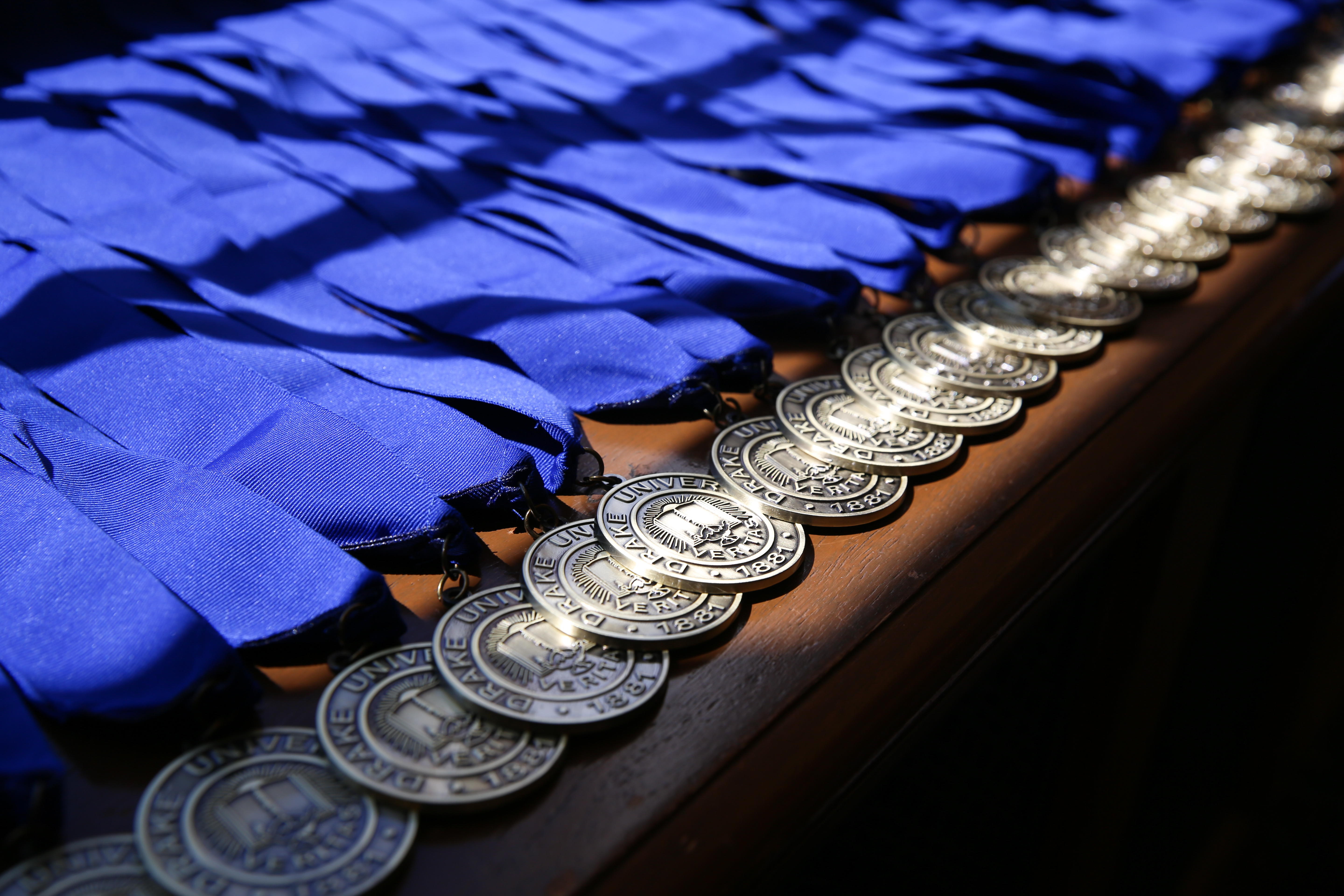 A series of medals with blue ribbons, awarded to students in Drake's Sports Media and Communication program