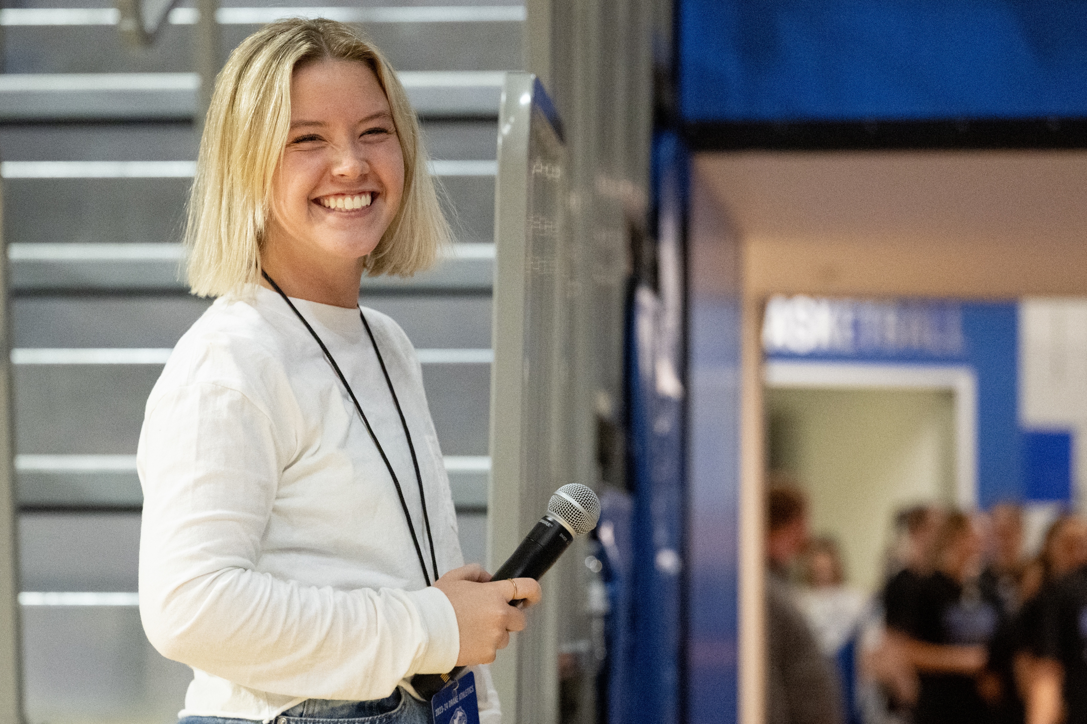 A student from Drake's Sports Media and Communication program smiles while holding a microphone before reporting on a game