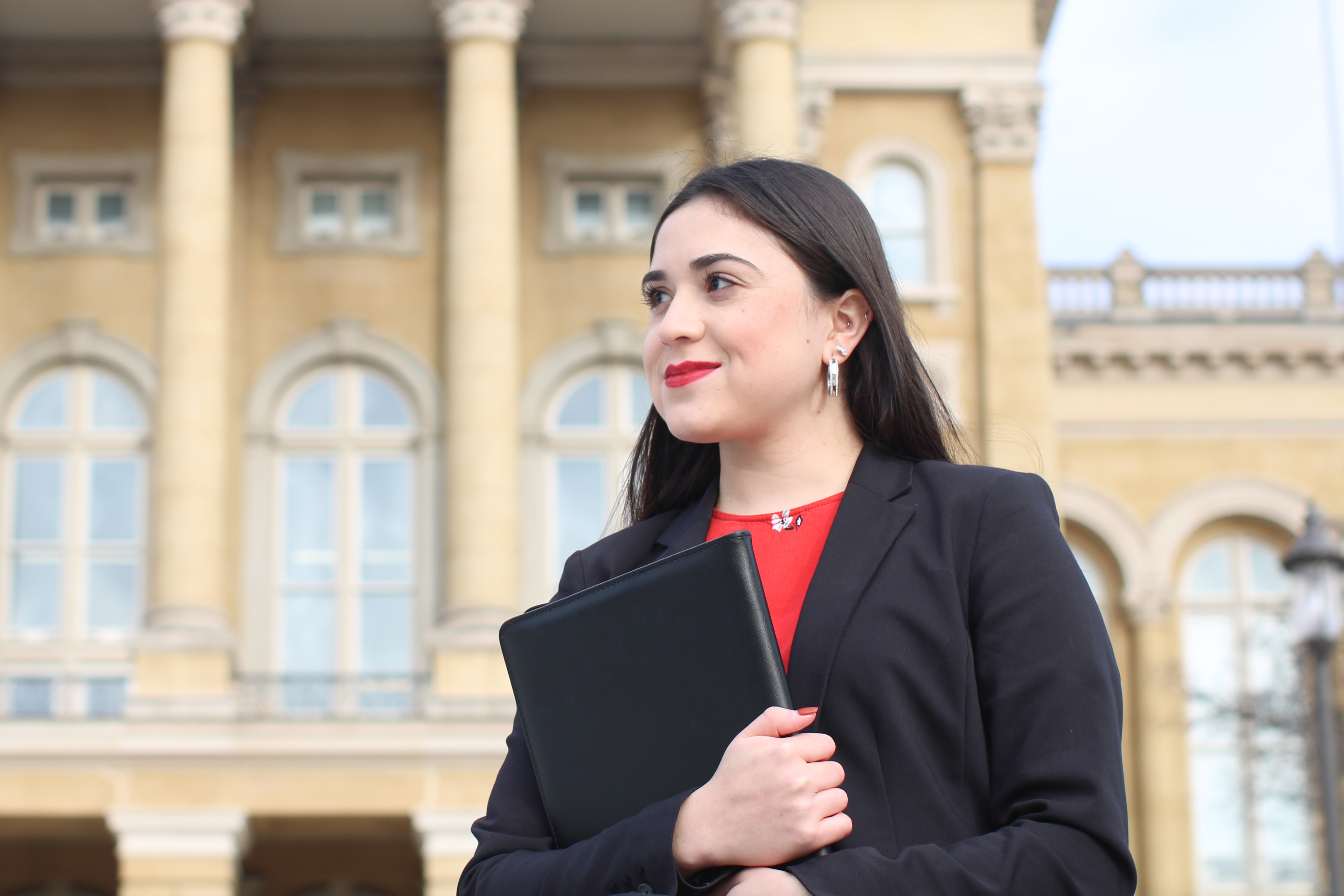 A Drake Strategic Political Communication student in a blazer holds a folder close while exiting the Iowa Capitol building