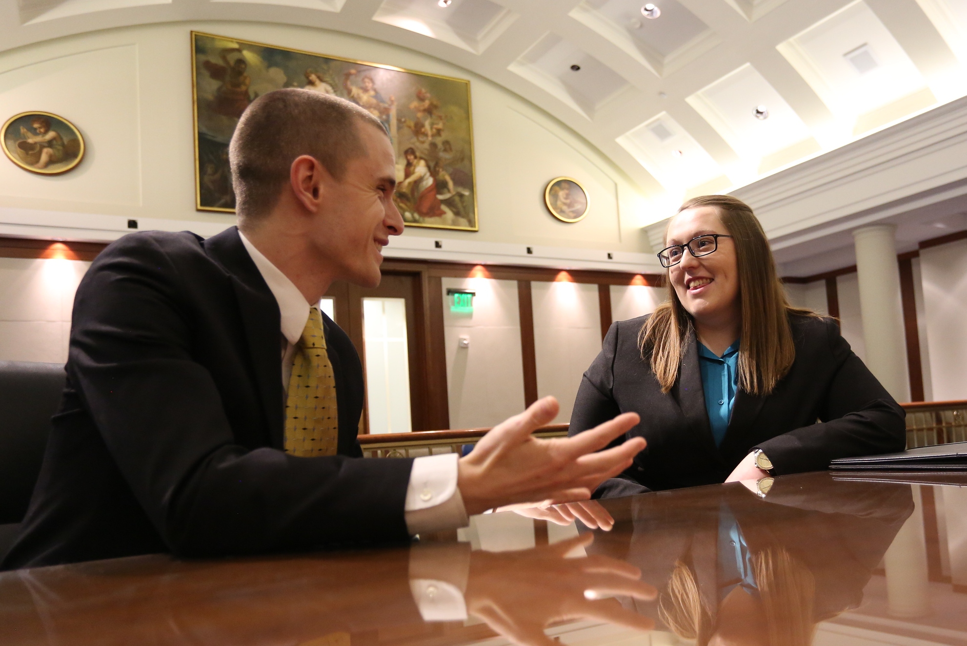 Two students from Drake's Strategic Political Communication program in dress clothes sit down fo a conversation in the Iowa State Capitol building