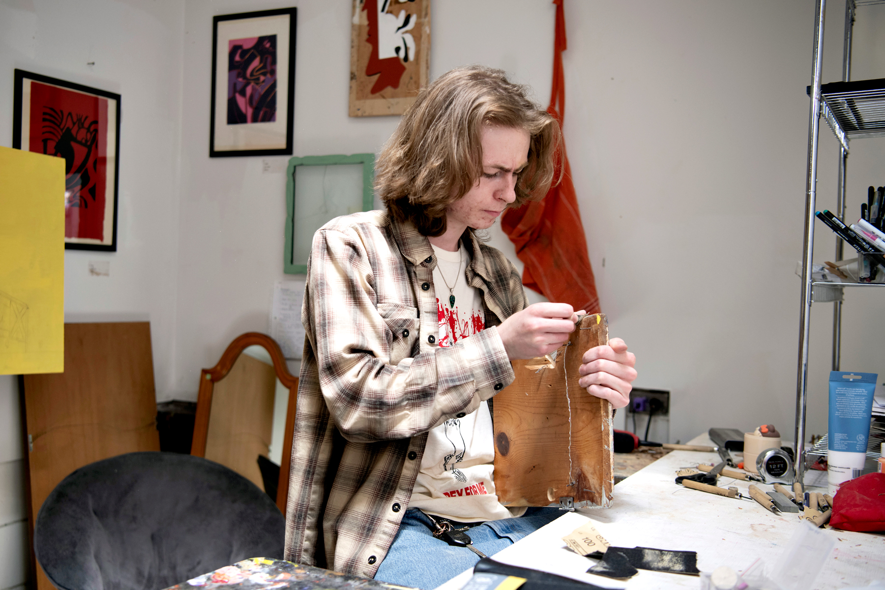 Sitting in a campus studio, a Drake Studio Art student finishes a piece of wood for a project
